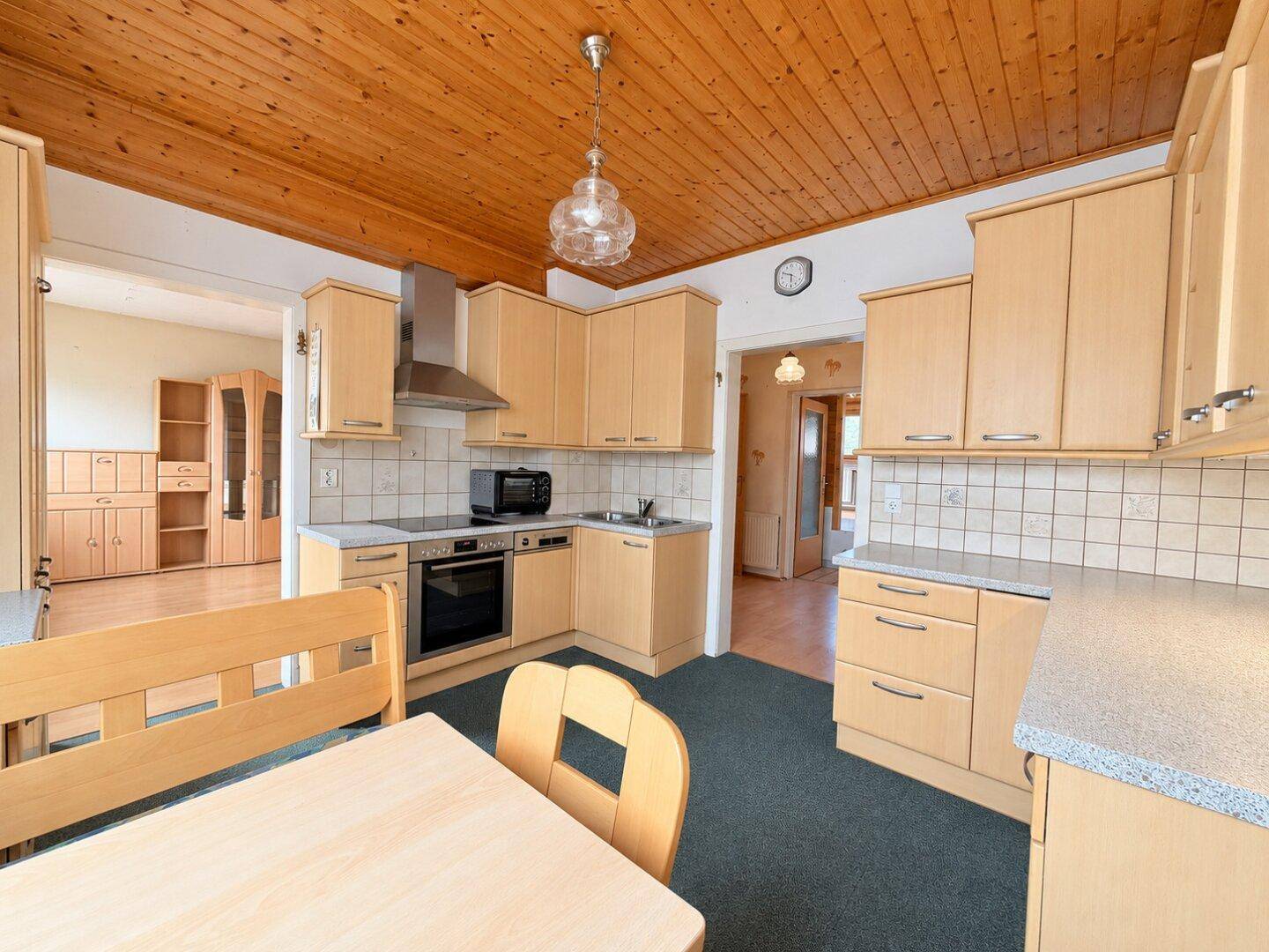 Funktionale Küche mit Holzschränken, integrierten Geräten und einem Essbereich im Zentrum.