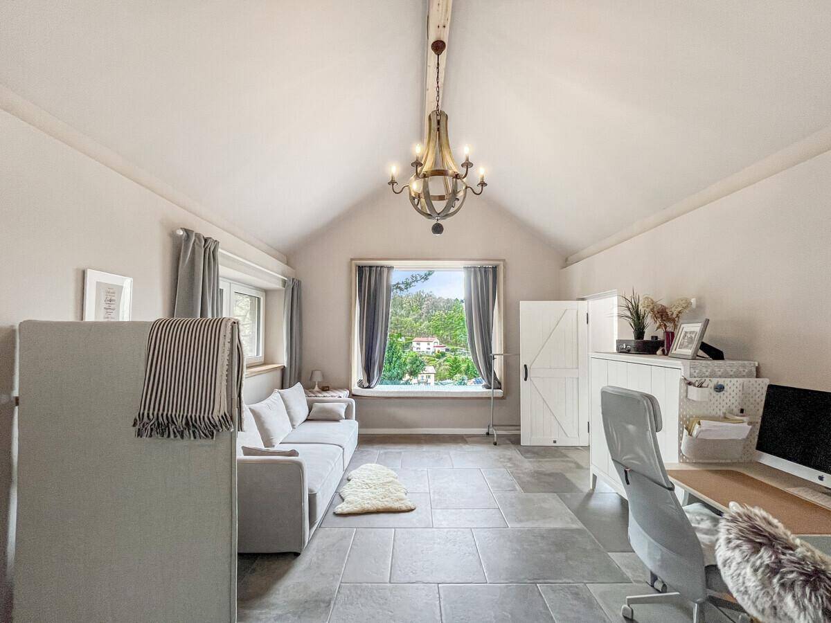 Helles Wohnzimmer mit Steinfliesen, hohen Decken und großem Fenster mit Ausblick.