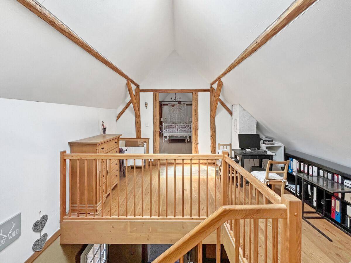Offener Dachbodenbereich mit Holzboden, Galerie und Blick auf ein weiteres Zimmer.