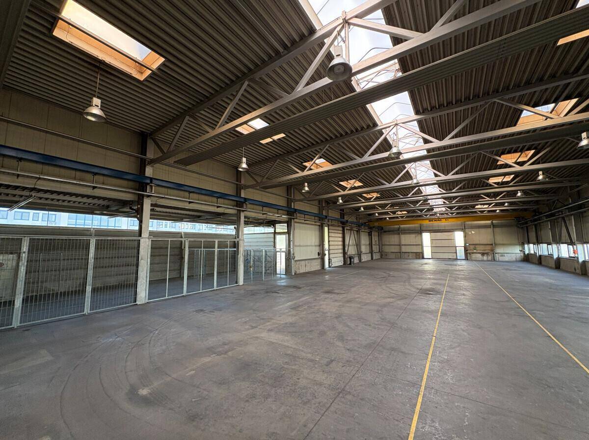 Leere Lagerhalle mit hohen Decken, Oberlichtern und großzügiger Fläche, bereit zur Nutzung.