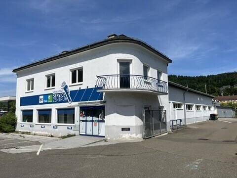 Vorderansicht eines Gewerbegebäudes mit Servicezentrum-Beschilderung, Balkon und barrierefreier Rampe.