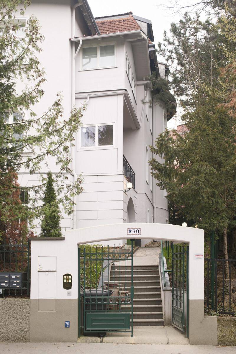 Eingangsbereich eines Gebäudes mit Tor, Treppe und der Hausnummer N30, umgeben von Bäumen.