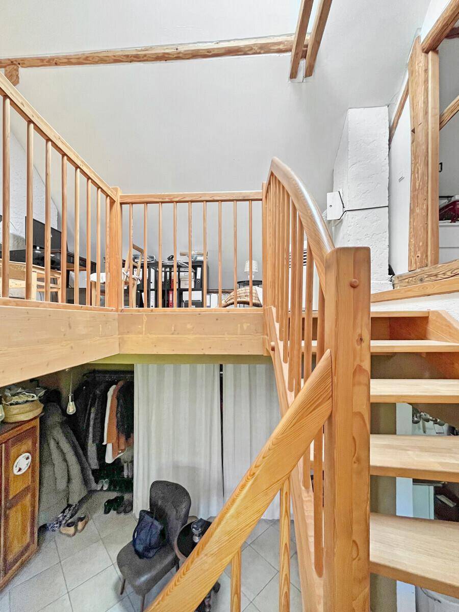 Holztreppe führt zu einem offenen Galeriebereich mit Blick auf den Eingang.