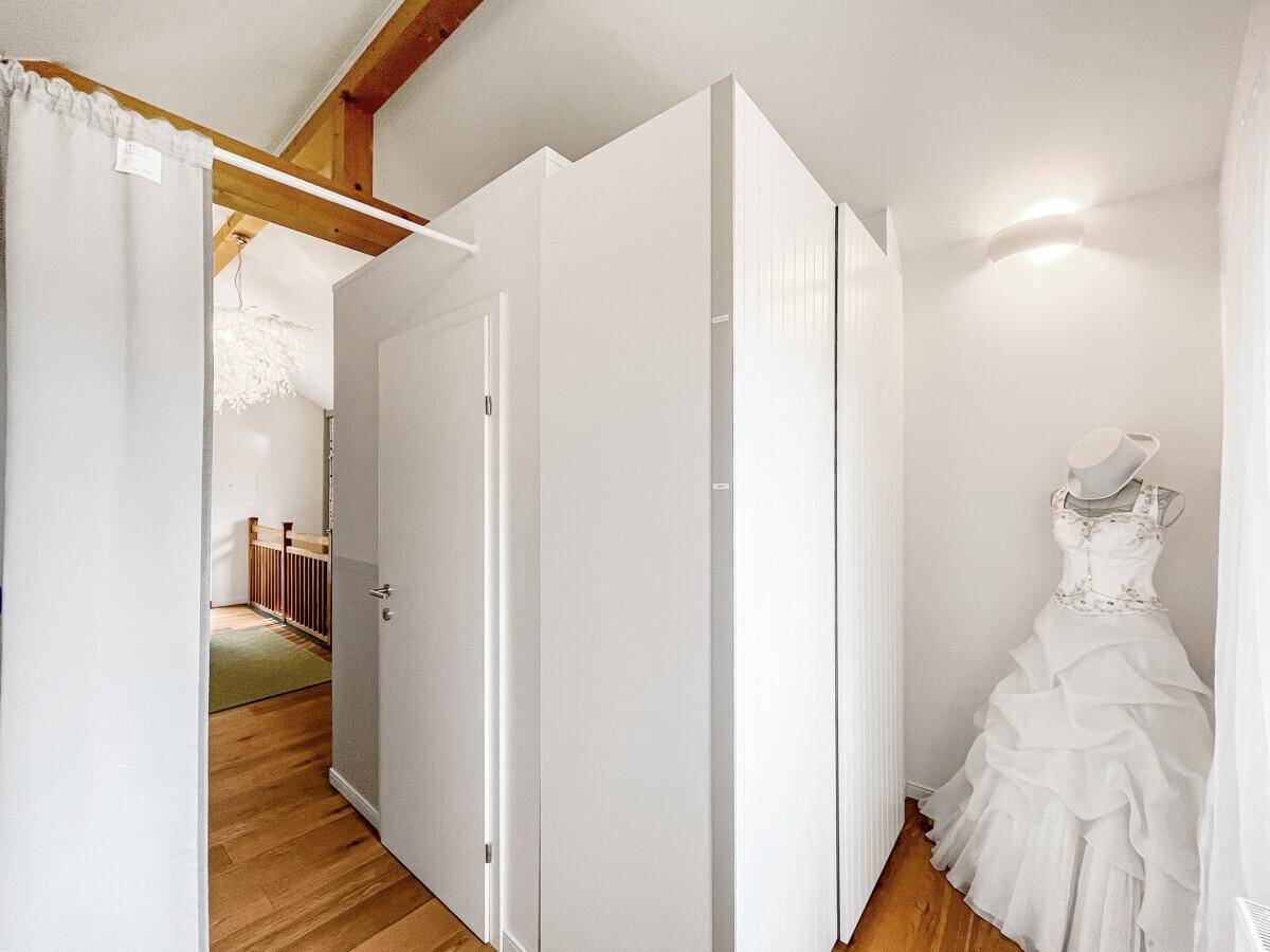 Heller Flur mit Holzboden und einer weißen Struktur, die möglicherweise einen begehbaren Kleiderschrank verbirgt.