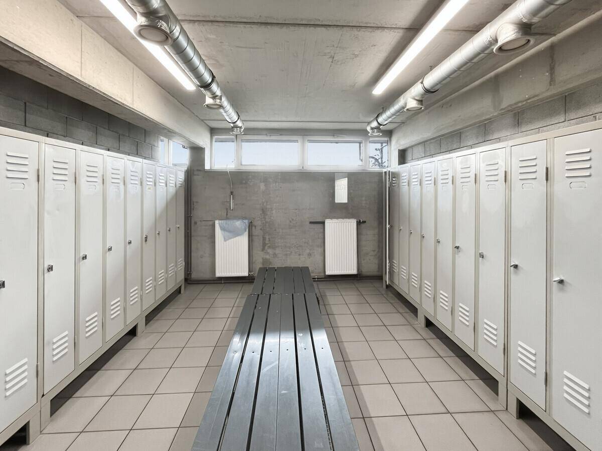 Geräumiger Umkleideraum mit Reihen von Spinden und einer Sitzbank in der Mitte, praktisch eingerichtet.