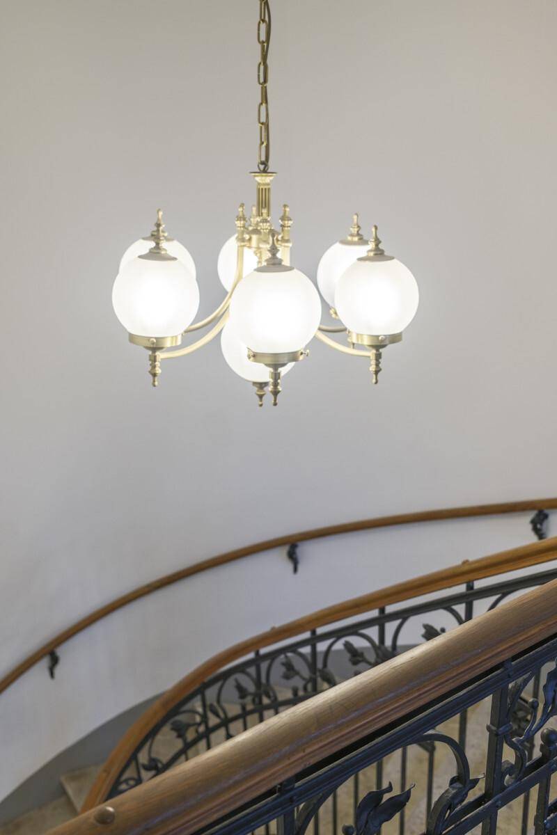 Elegantes Treppenhaus mit kunstvollem Metallgeländer und einem klassischen Messing-Kronleuchter.