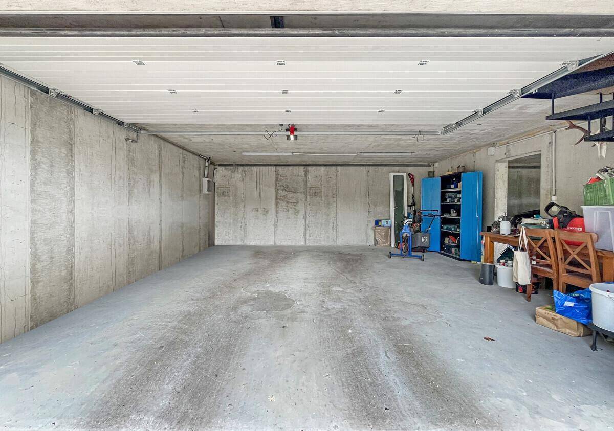 Geräumige Garage mit Betonwänden, Rolltor und Stauraum für Werkzeuge und Geräte.