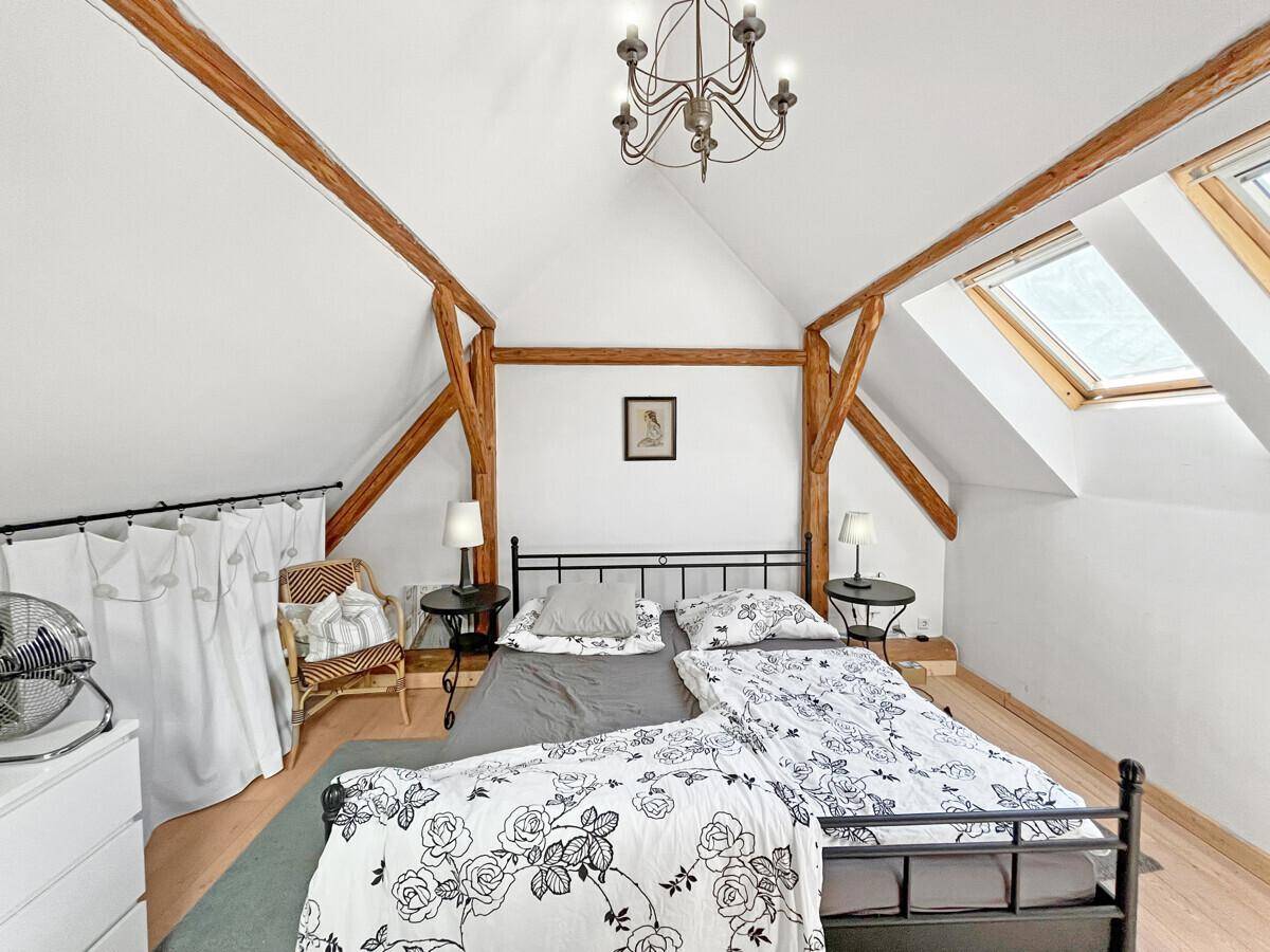 Gemütliches Schlafzimmer im Dachgeschoss mit Holzbalken, Dachfenstern und Doppelbett.