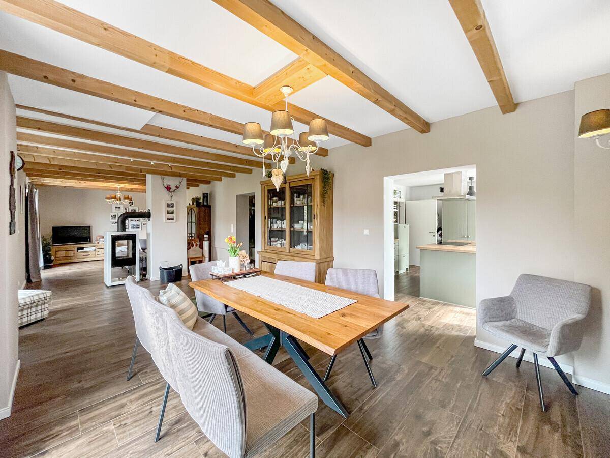 Geräumiger Essbereich mit Holztisch, Holzbalkendecke und offener Verbindung zur Küche.