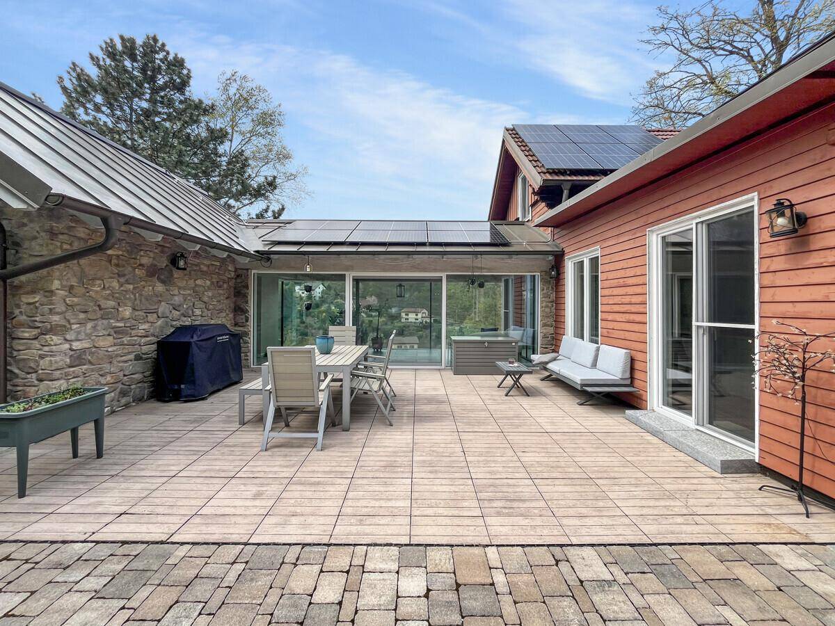 Weitläufige Terrasse mit Sitzgelegenheiten, Grill und Zugang zum Haus.