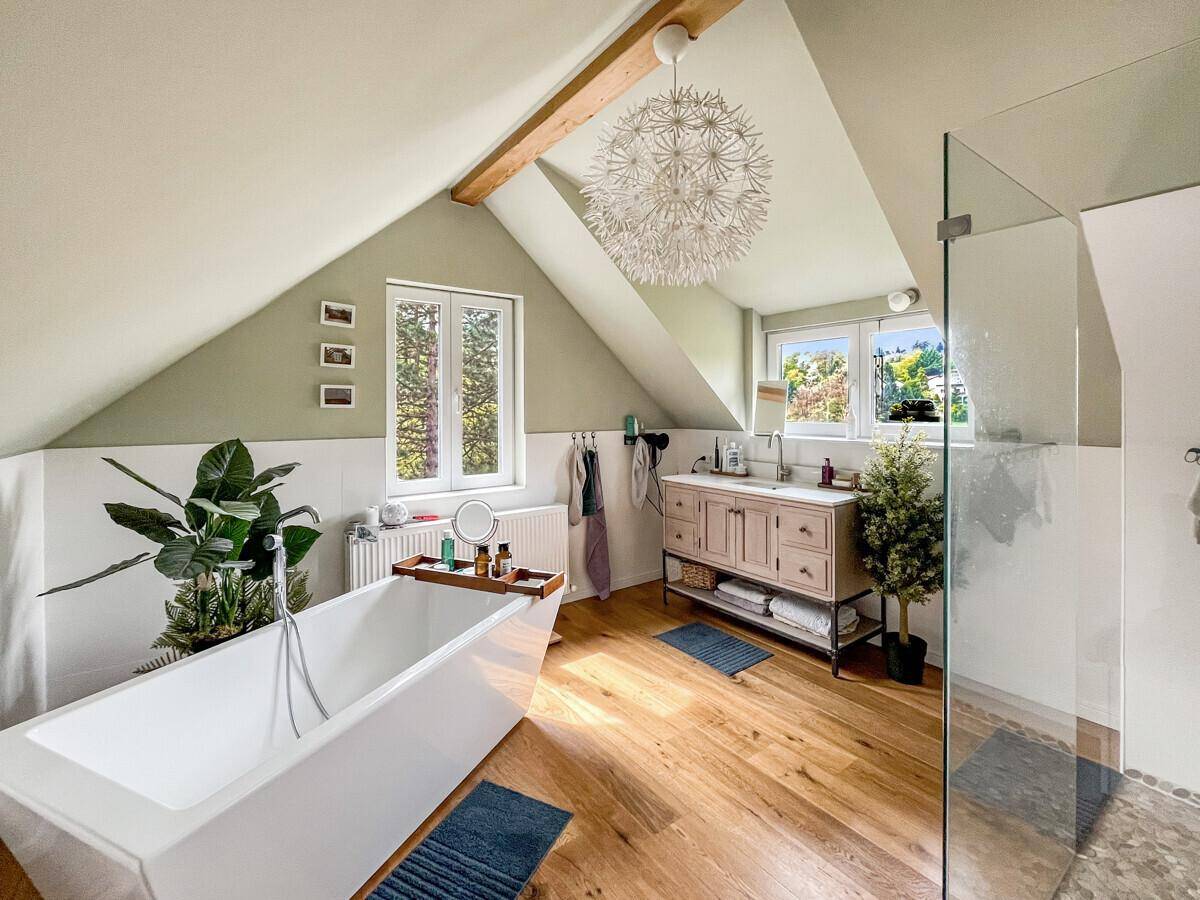 Modernes Badezimmer im Dachgeschoss mit freistehender Badewanne, Dusche und Holzboden.