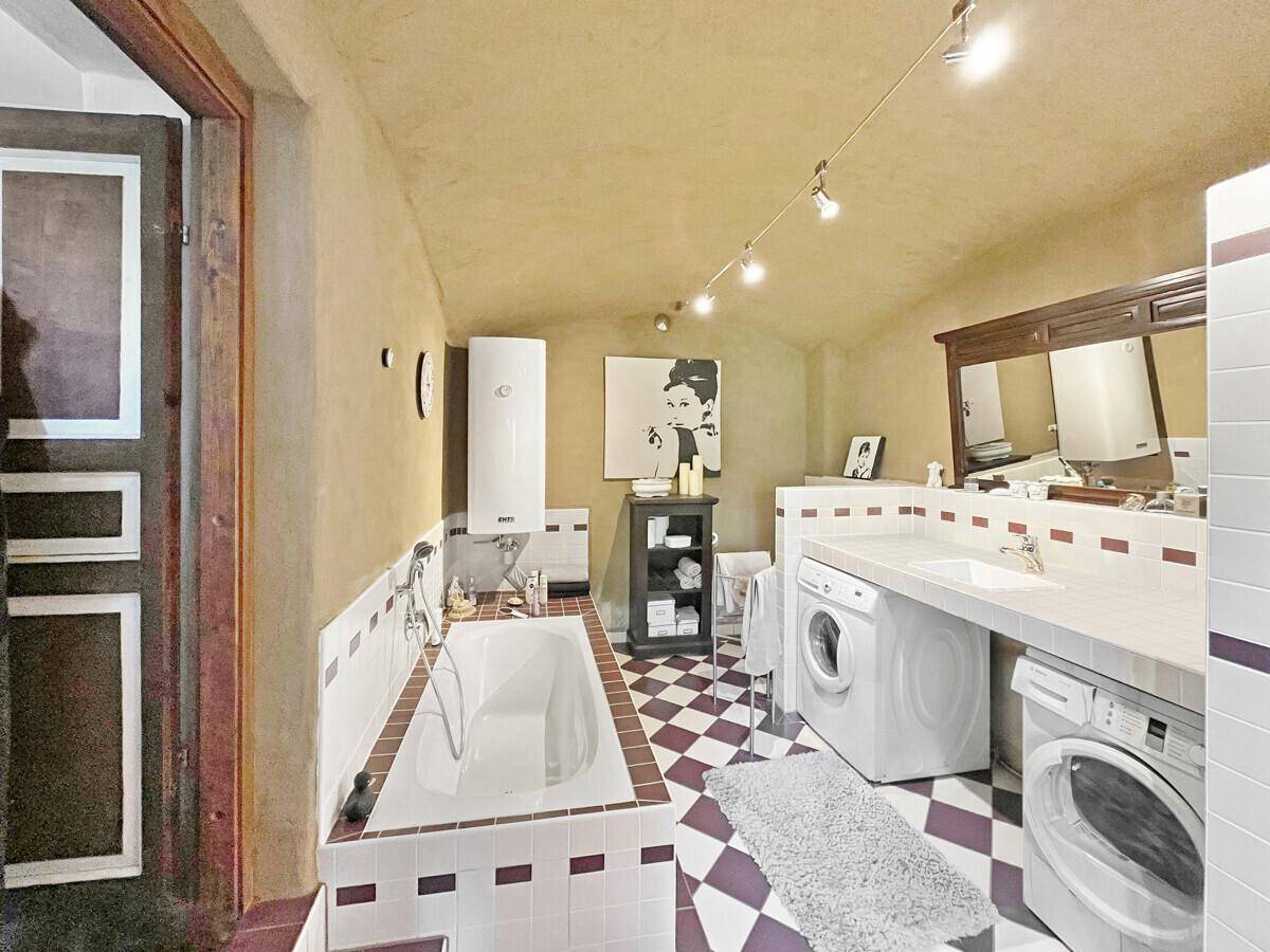 Geräumiges Badezimmer mit Badewanne, Waschmaschinen und kariertem Fliesenboden.