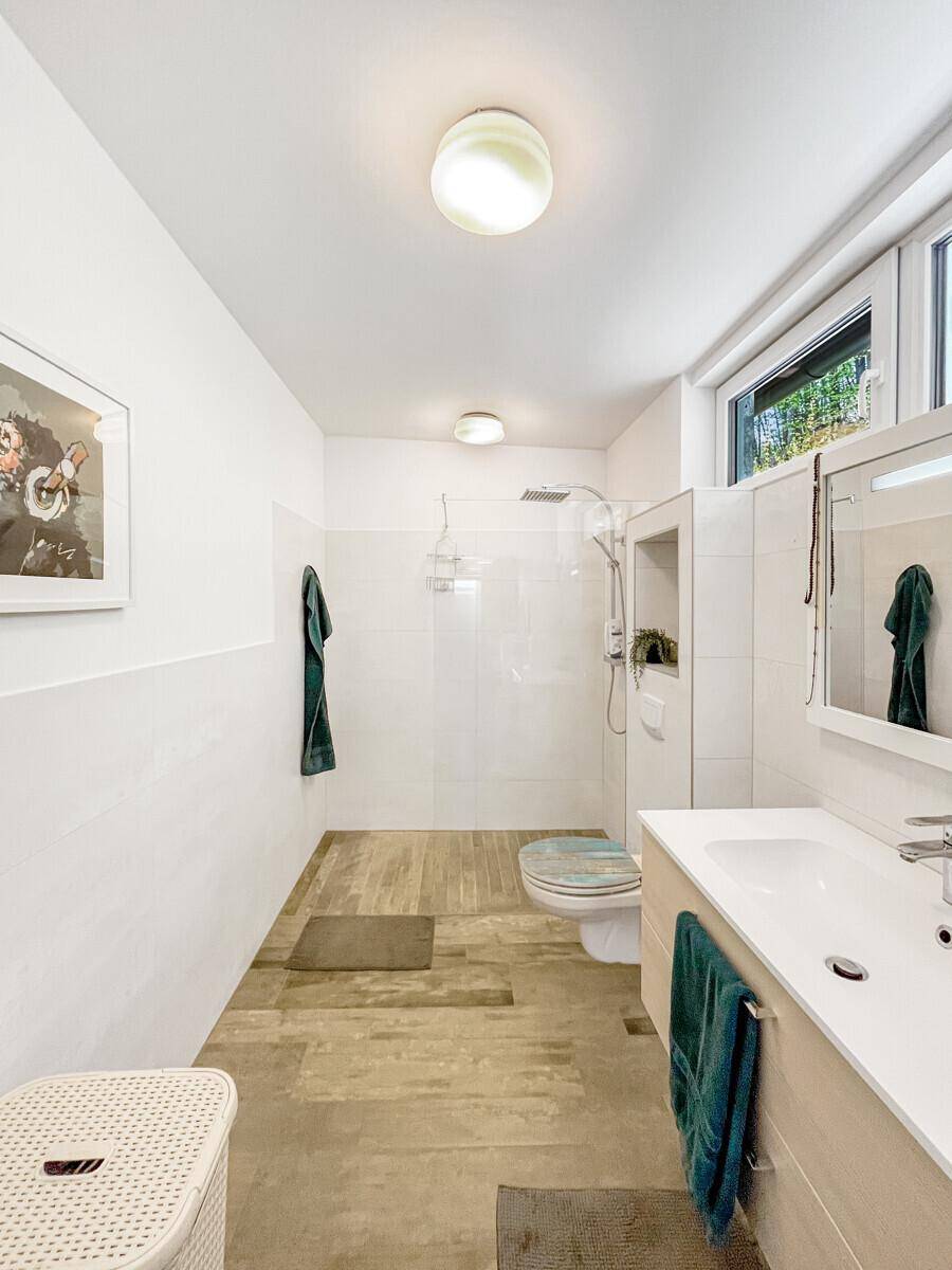 Modernes Badezimmer mit begehbarer Dusche, Wand-WC und Fenster.