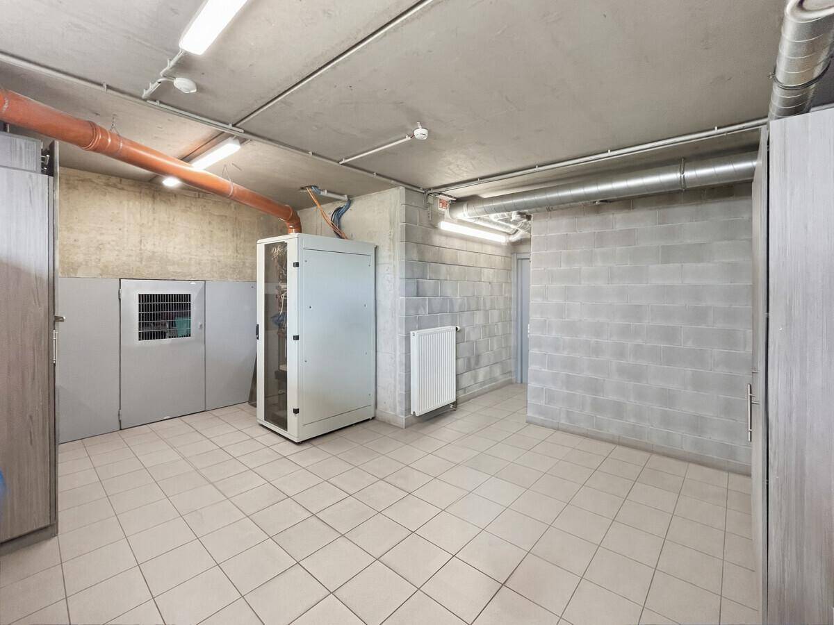 Technikraum mit Serverrack, Betonwänden und Fliesenboden, für technische Infrastruktur genutzt.