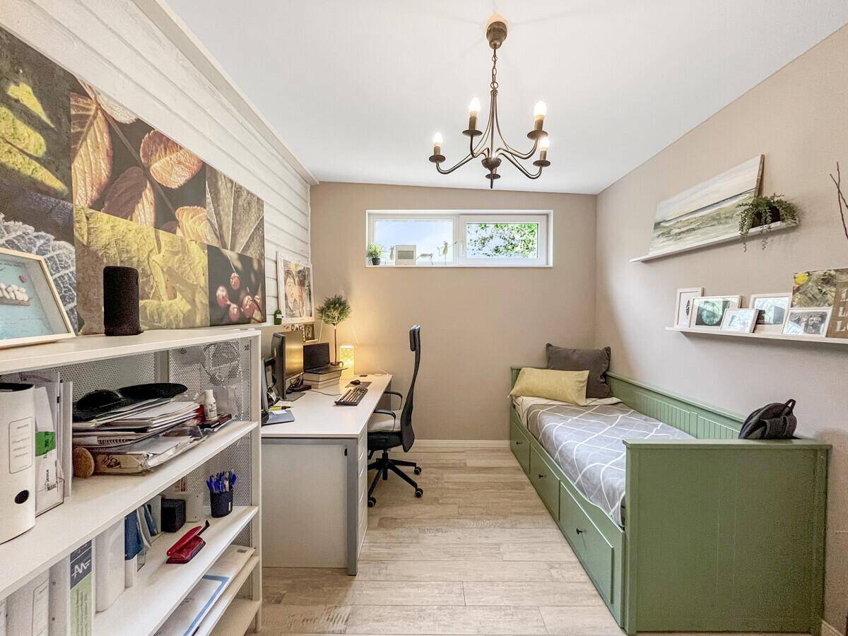 Helles Arbeitszimmer mit Schreibtisch, Regal und Tagesbett mit Stauraum.