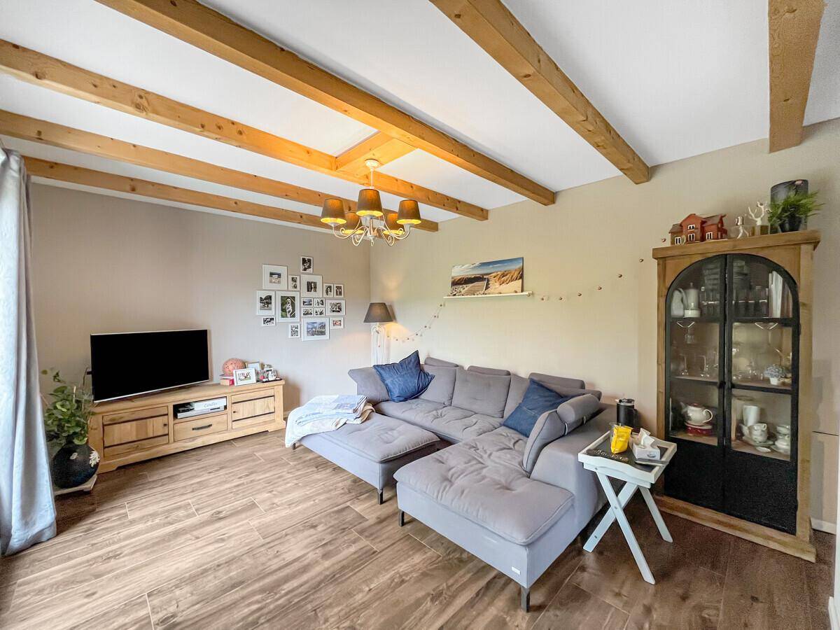 Gemütliches Wohnzimmer mit Holzbalkendecke, großem Sofa und Holzboden.