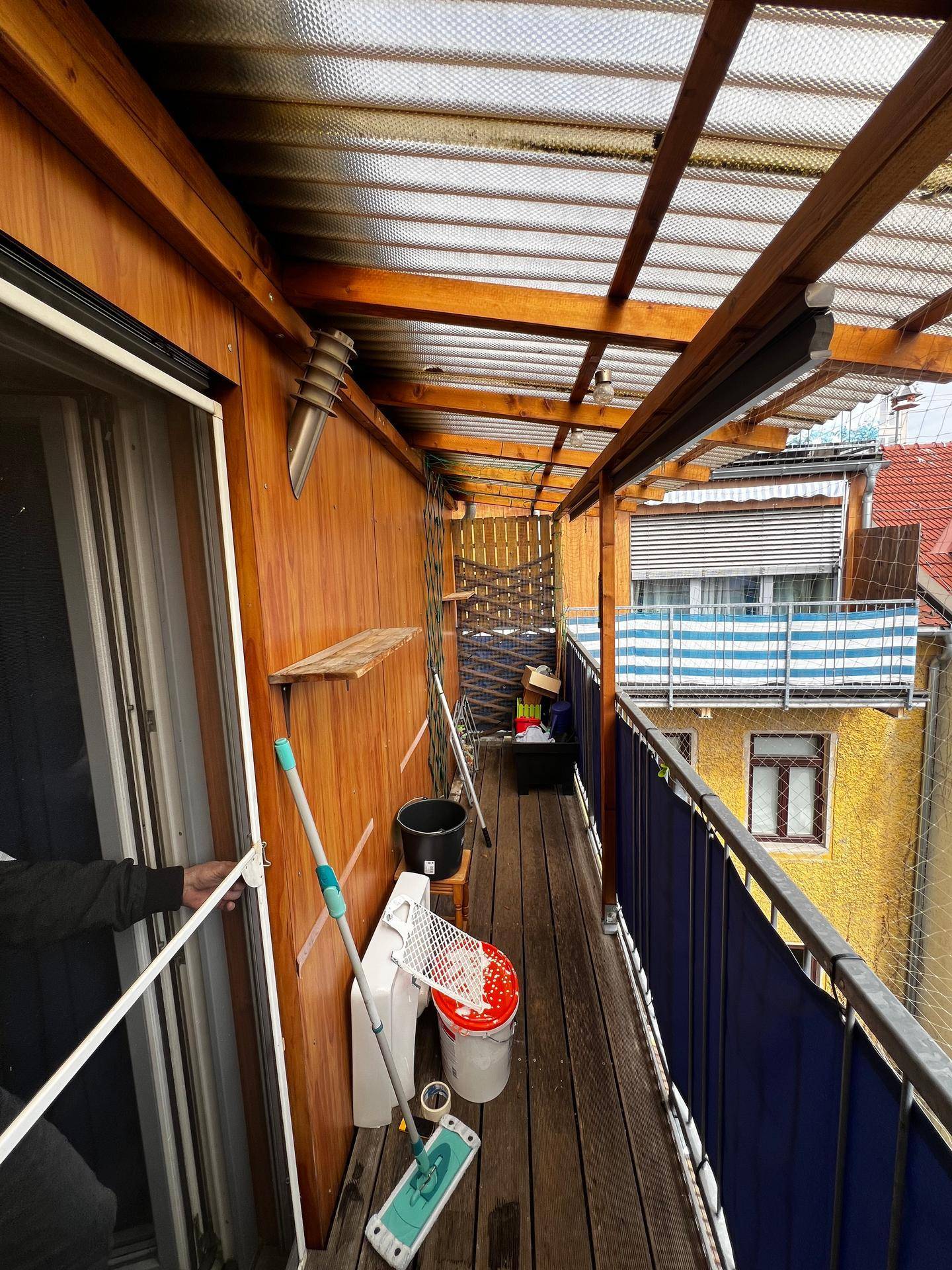 Überdachter Balkon mit Holzverkleidung und Blick auf die umliegenden Gebäude.