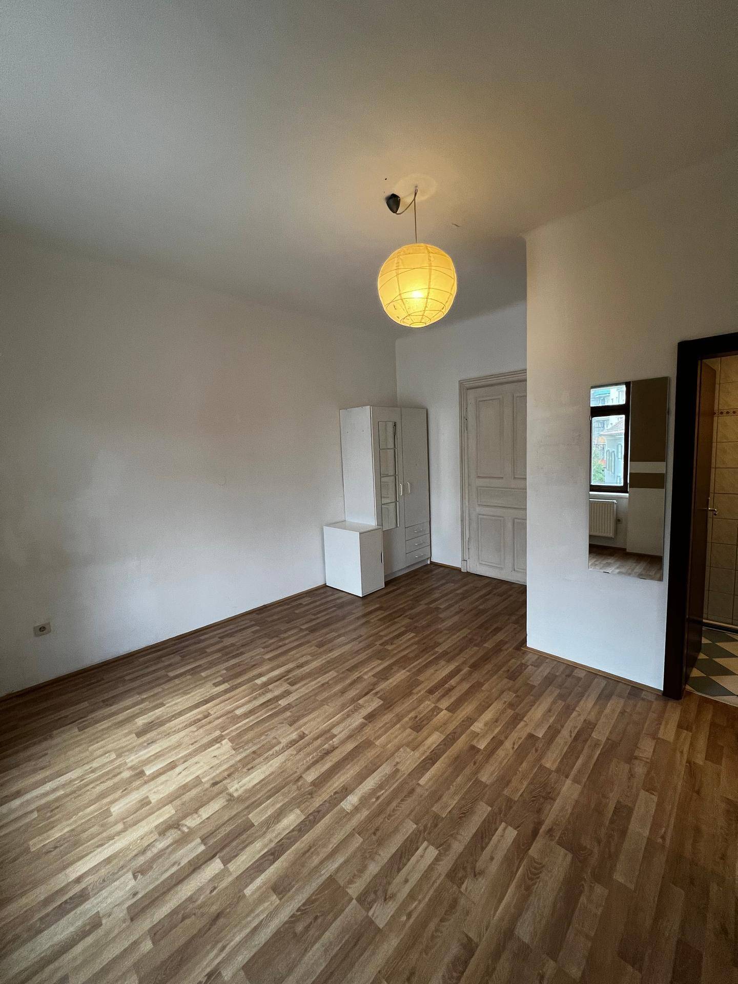 Heller Flur mit Laminatboden, weißem Schrank und Zugang zu weiteren Zimmern.