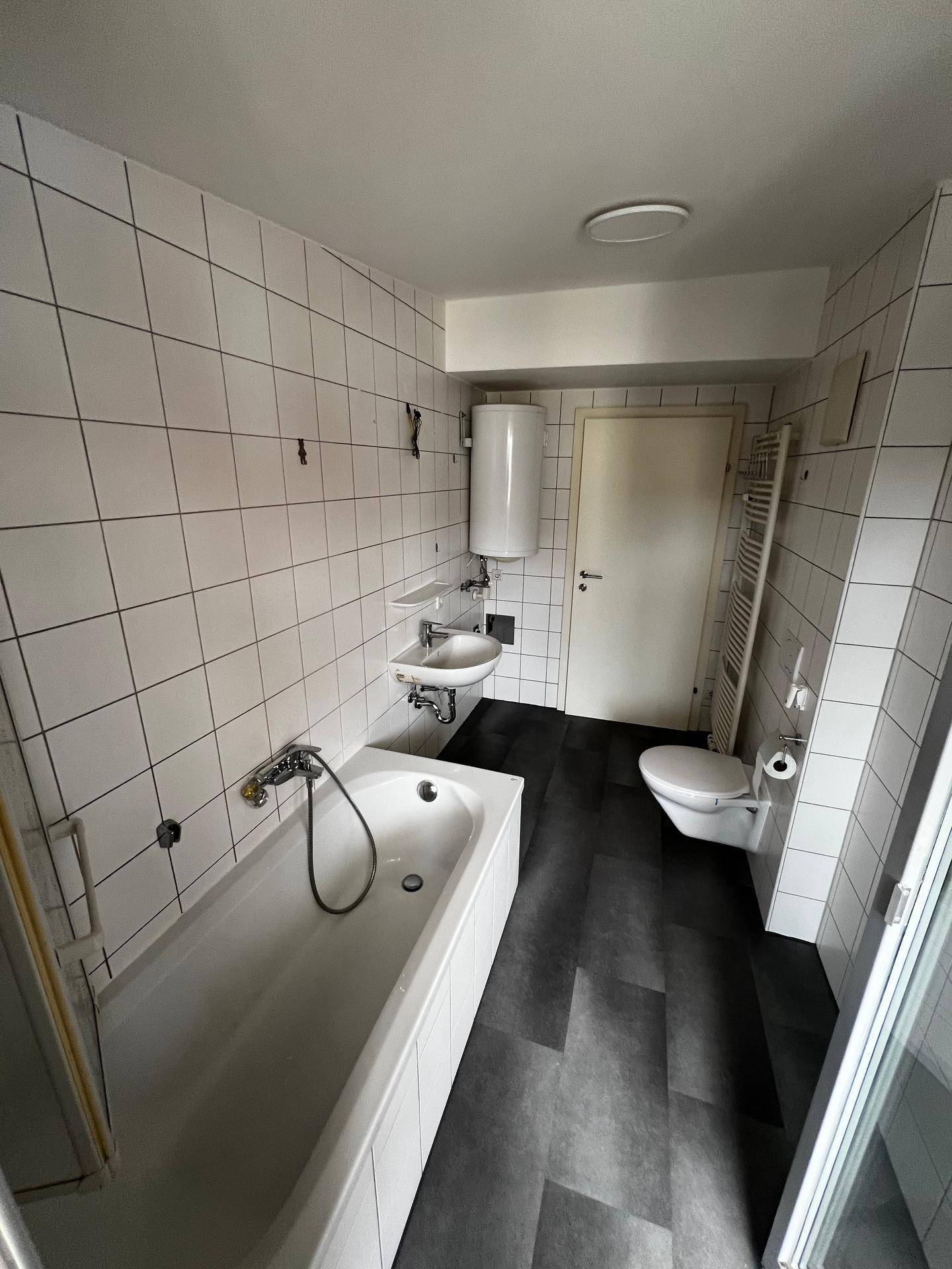 Funktionales Badezimmer mit Badewanne, Waschbecken, Toilette und Handtuchheizkörper.