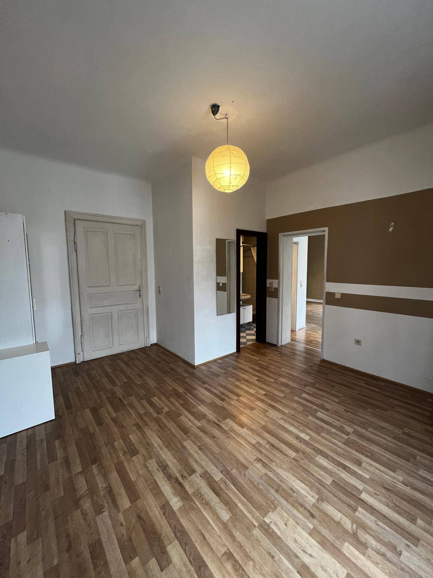Eingangsbereich oder Flur mit Laminatboden, heller Wandfarbe und mehreren Türen.