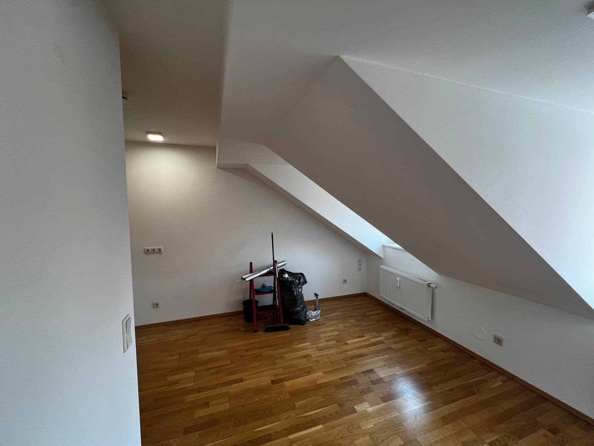 Heller Raum mit Holzboden und markanten Dachschrägen, ideal für individuelle Gestaltung.