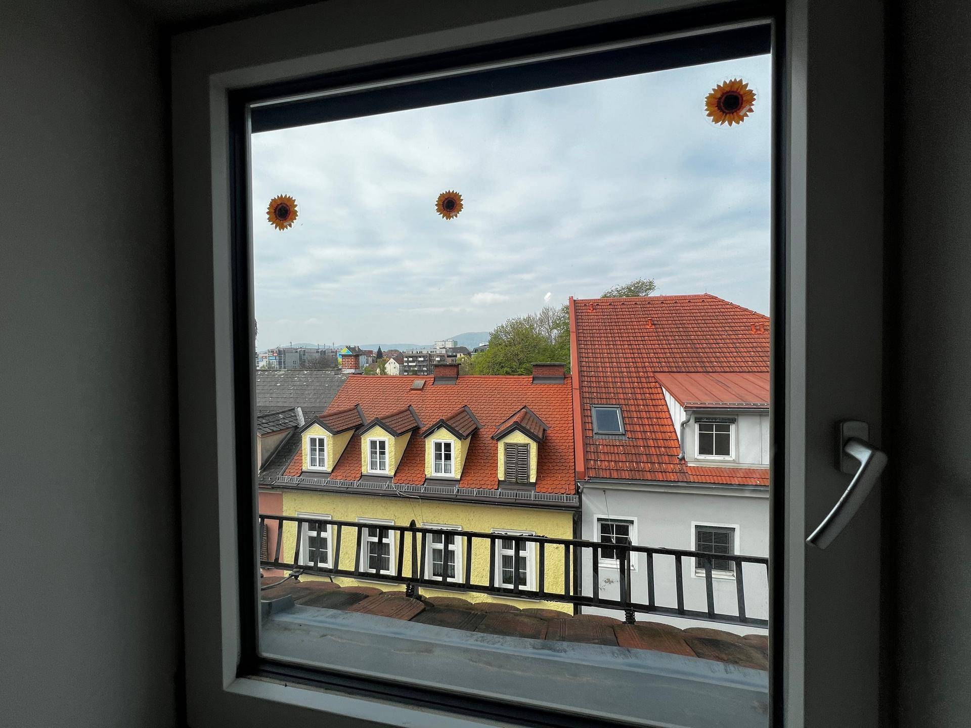 Fenster mit Blick auf die roten Dächer der Stadt und die umliegende Landschaft.