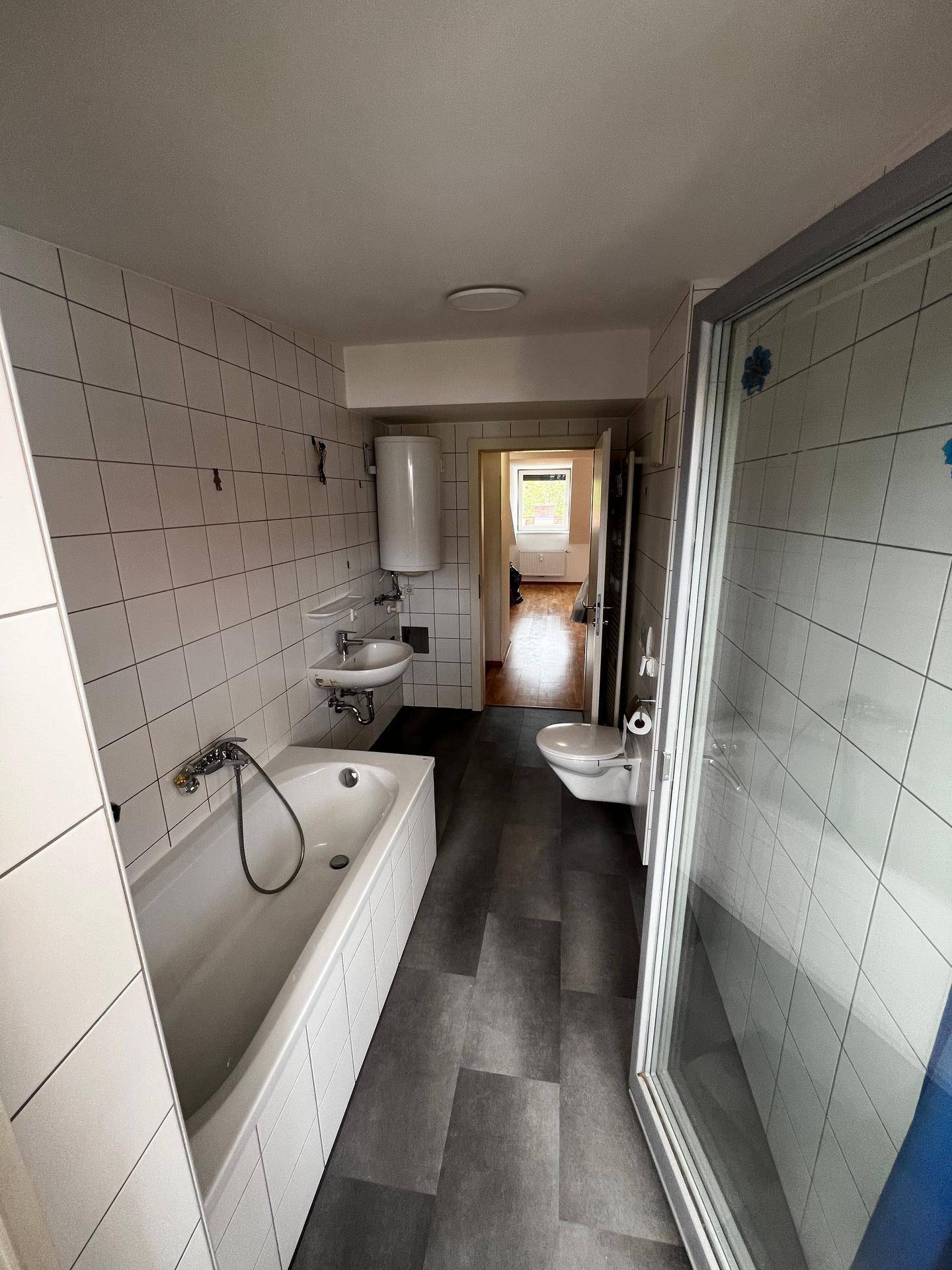 Helles Badezimmer mit Badewanne, Waschbecken und Duschabtrennung.