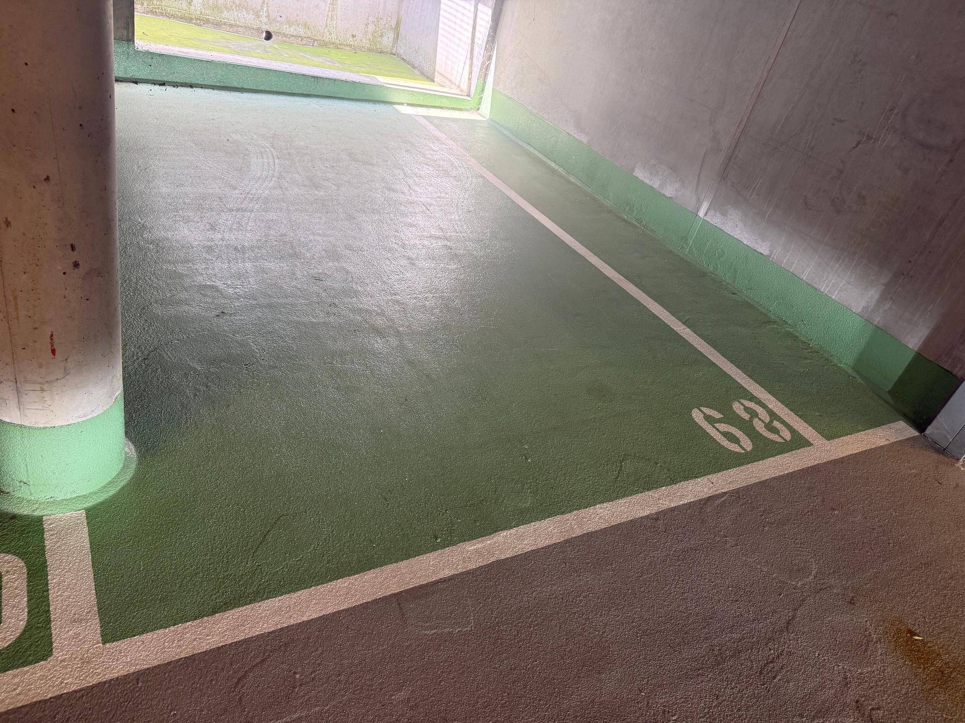 Detailansicht eines Tiefgaragenstellplatzes mit grünen Bodenmarkierungen und robustem Betonboden.