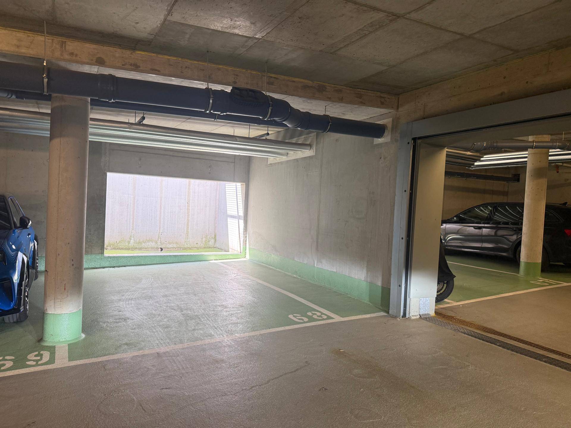 Geräumiger Tiefgaragenstellplatz mit Zugang zu weiteren Parkbereichen und natürlichem Lichteinfall.