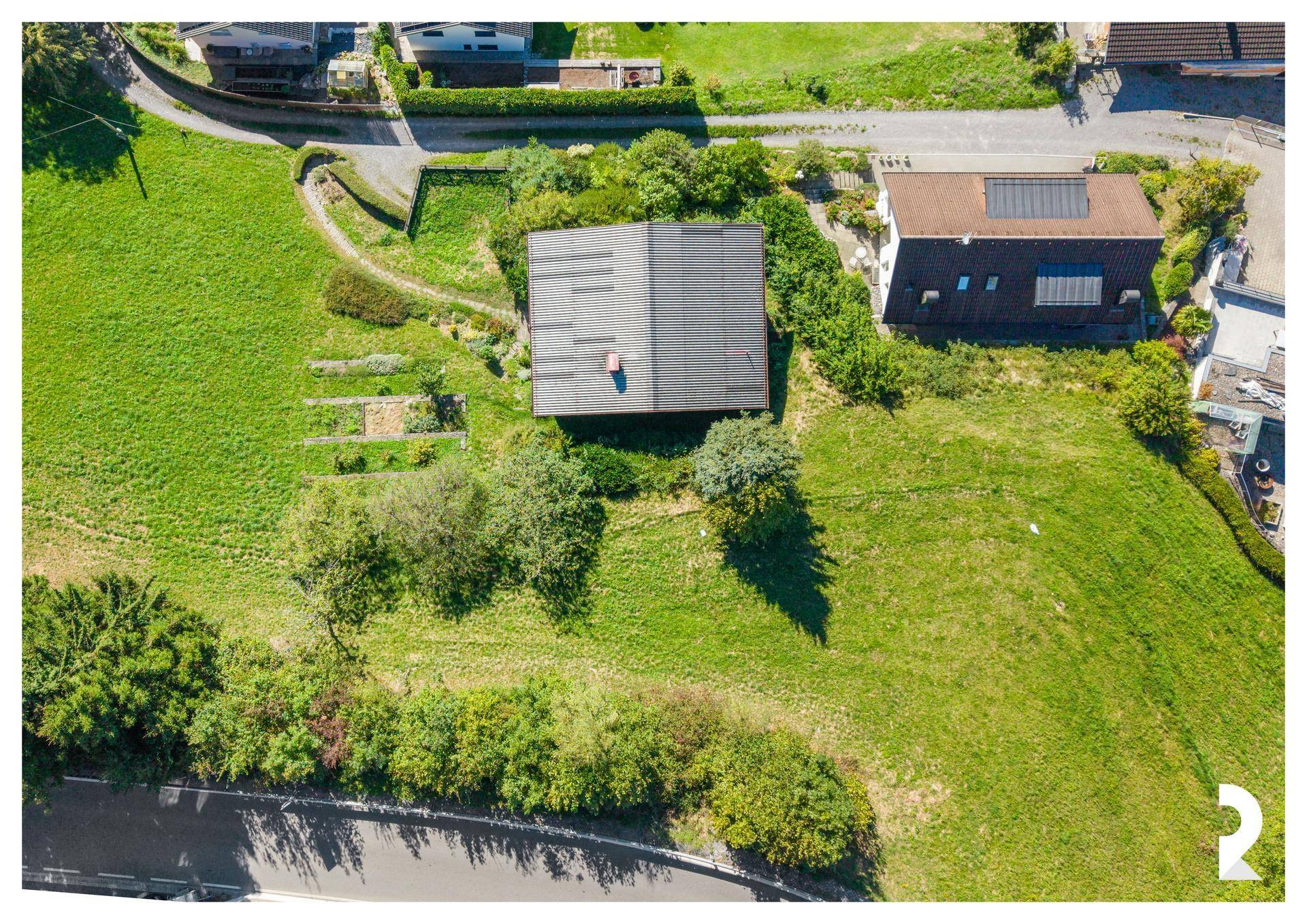 Senkrechte Luftaufnahme des Hauses mit seinem Dach und dem weitläufigen grünen Grundstück.
