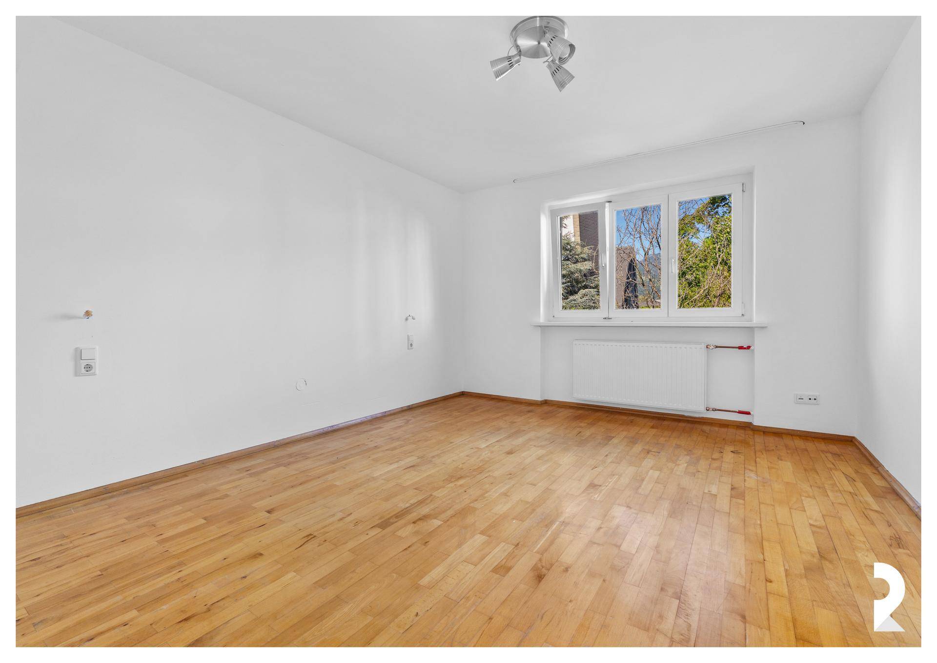 Helles Schlafzimmer mit Holzboden, weißen Wänden und großen Fenstern.