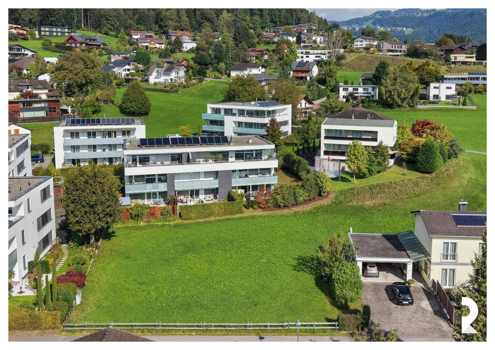 Luftaufnahme des Baugrundstücks mit modernen Mehrfamilienhäusern und grüner Umgebung.