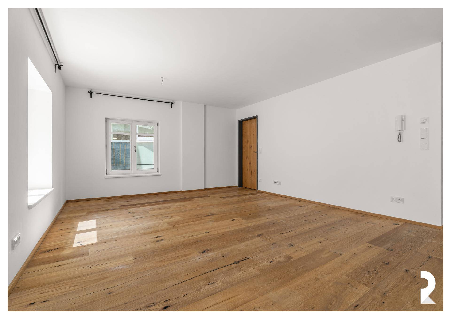 Ruhiger, heller Raum mit Holzboden und einem Fenster, ideal als Schlafzimmer oder Arbeitszimmer nutzbar.