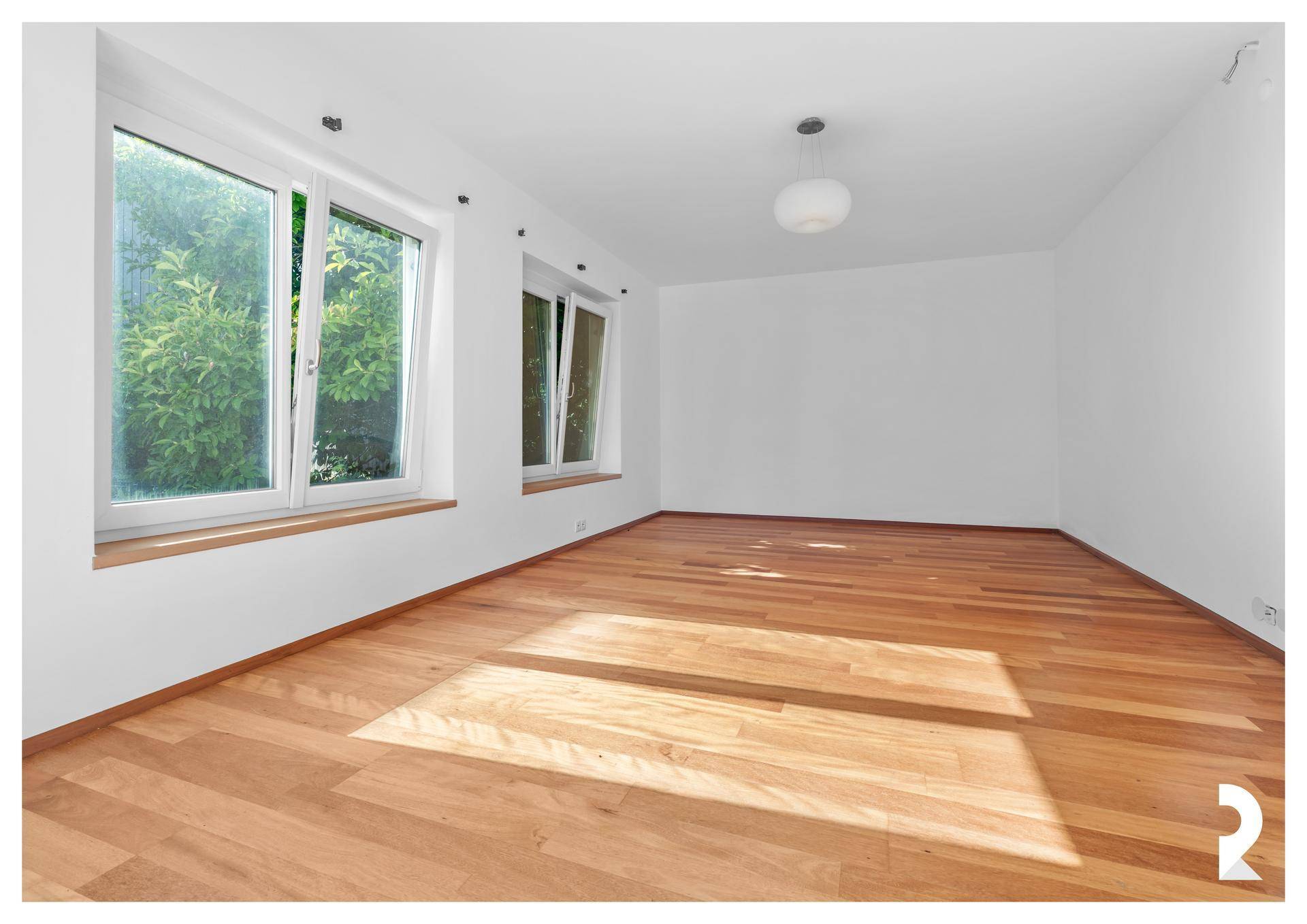 Helles Wohnzimmer mit neuem Parkettboden und großen Fenstern mit Blick ins Grüne.