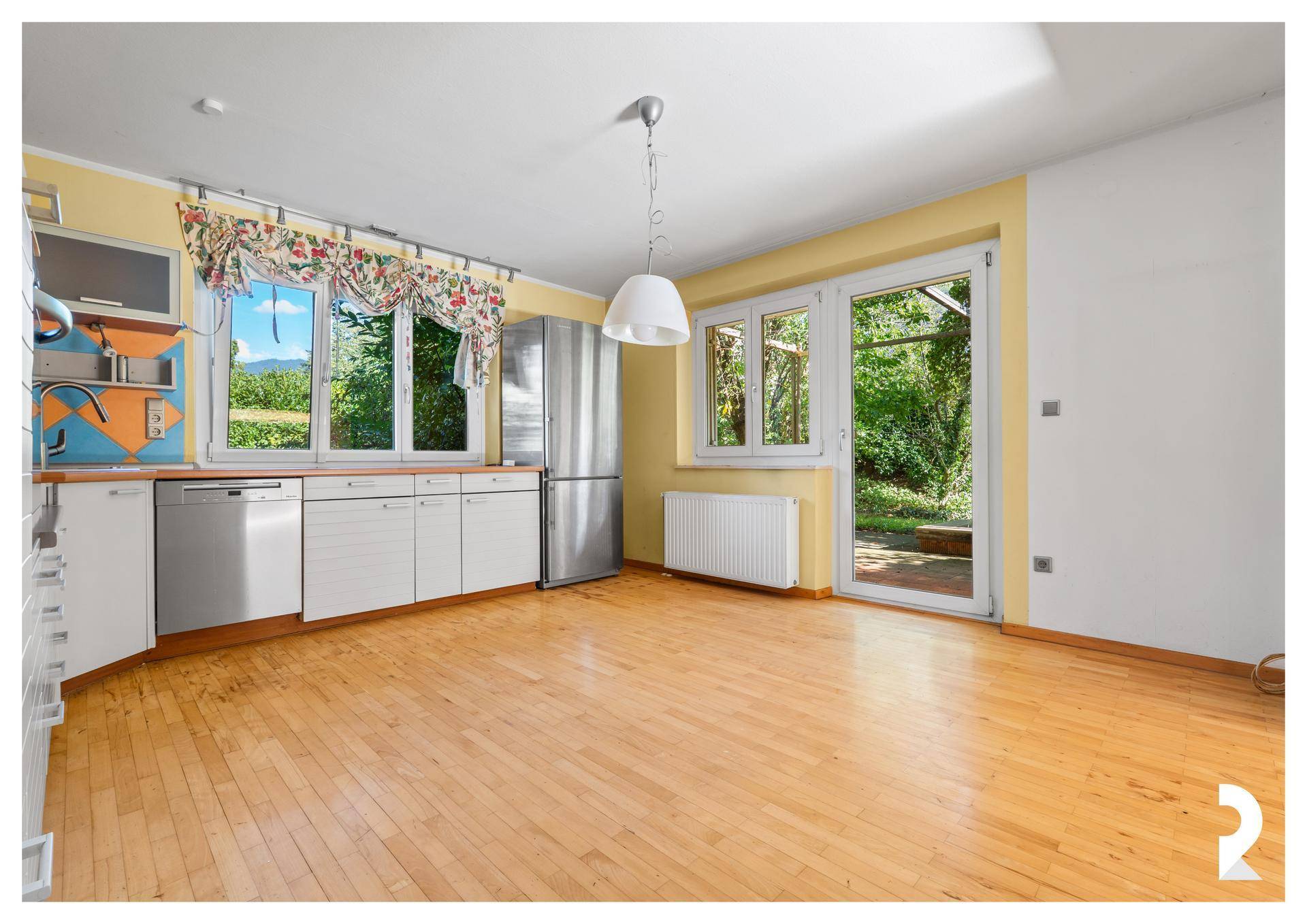 Helle Küche mit gelben Wänden, Holzboden und Zugang zum Gartenbereich.