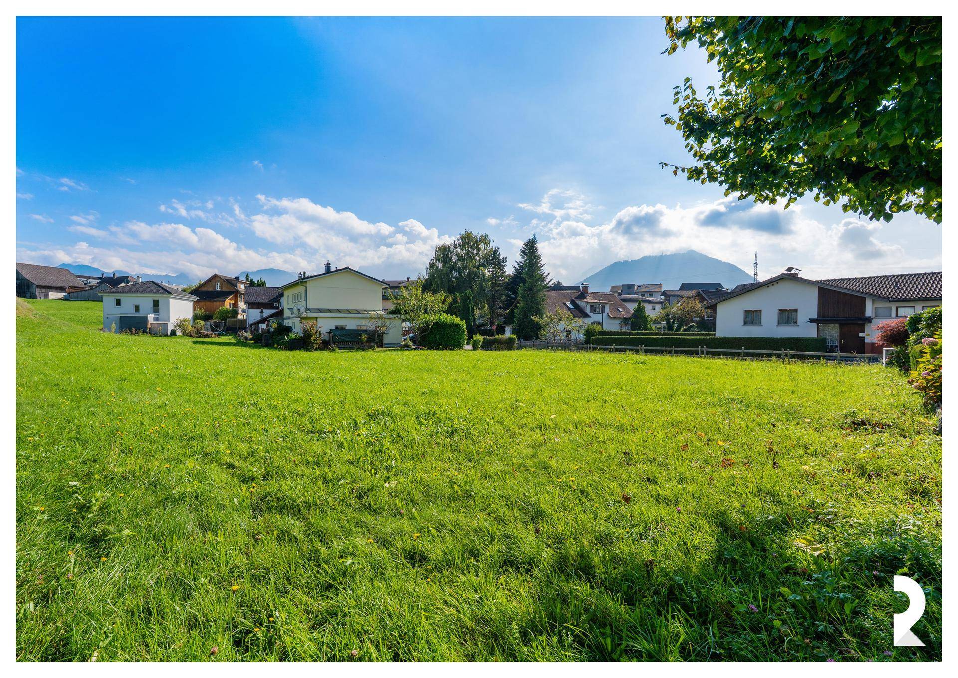 Großzügiges Baugrundstück mit weitem Blick auf die umliegende Berglandschaft und blauen Himmel.