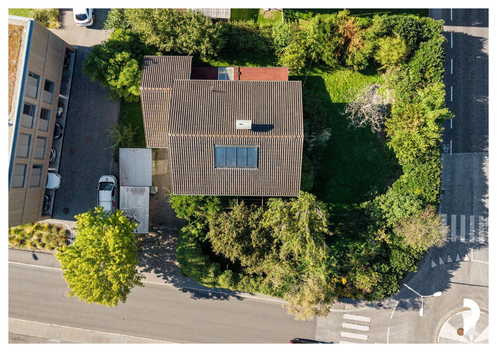 Senkrechte Luftaufnahme des Hauses mit Satteldach, Garten und der angrenzenden Straßenführung.