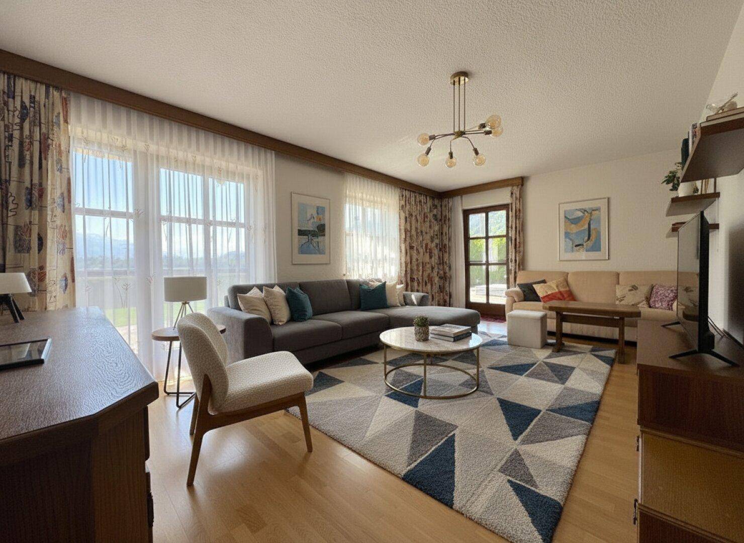 Helles Wohnzimmer mit bequemer Sitzecke, großzügigen Fenstern und Bergblick.