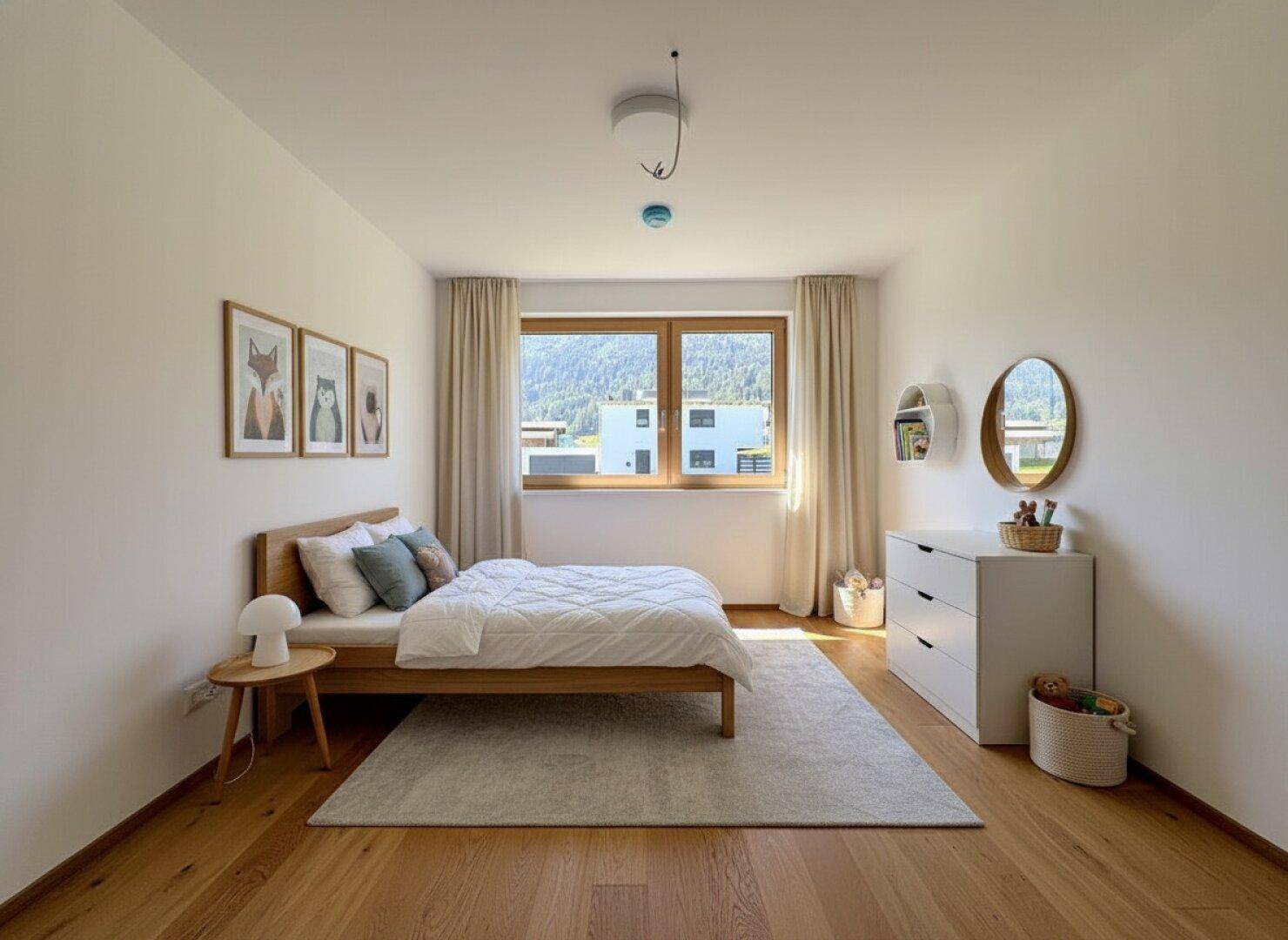 Freundliches Kinder- oder Gästezimmer mit Holzboden, hellem Bett und einem Fenster mit Blick ins Grüne.