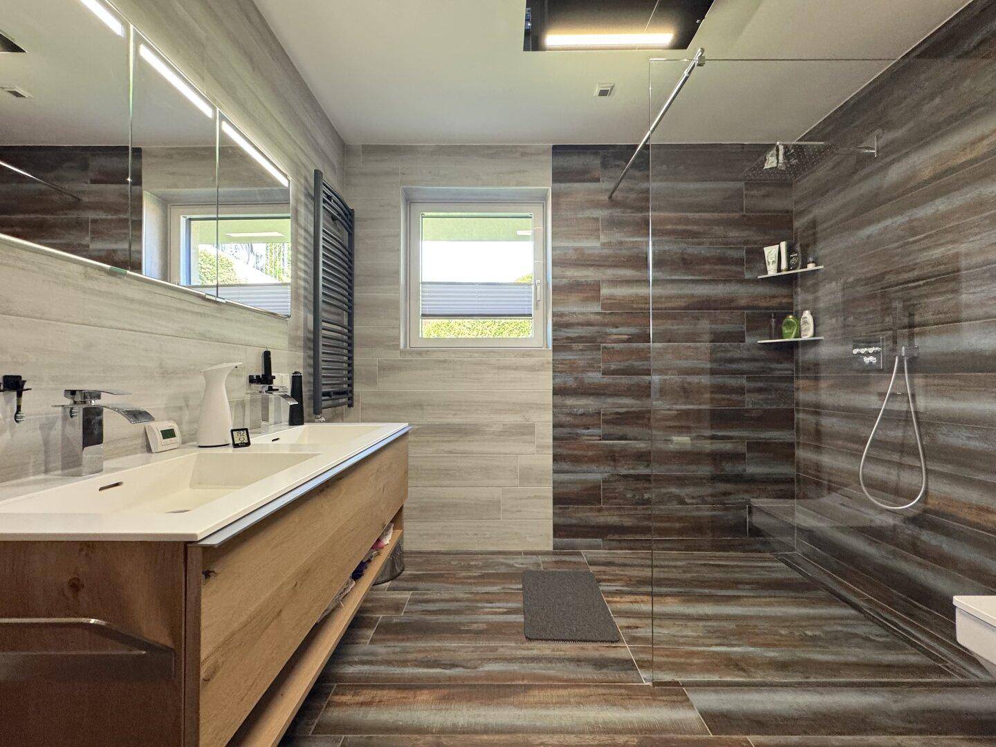 Modernes Badezimmer mit Doppelwaschbecken, großer begehbarer Dusche und Fenster.