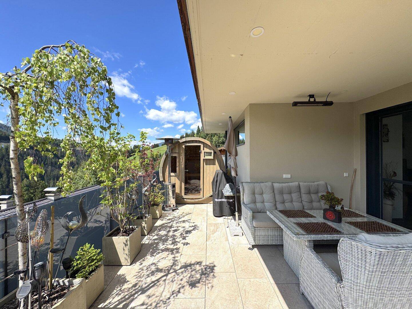 Weitläufige Terrasse mit Außen-Sauna, Essbereich und Panoramablick auf die umliegende Natur.