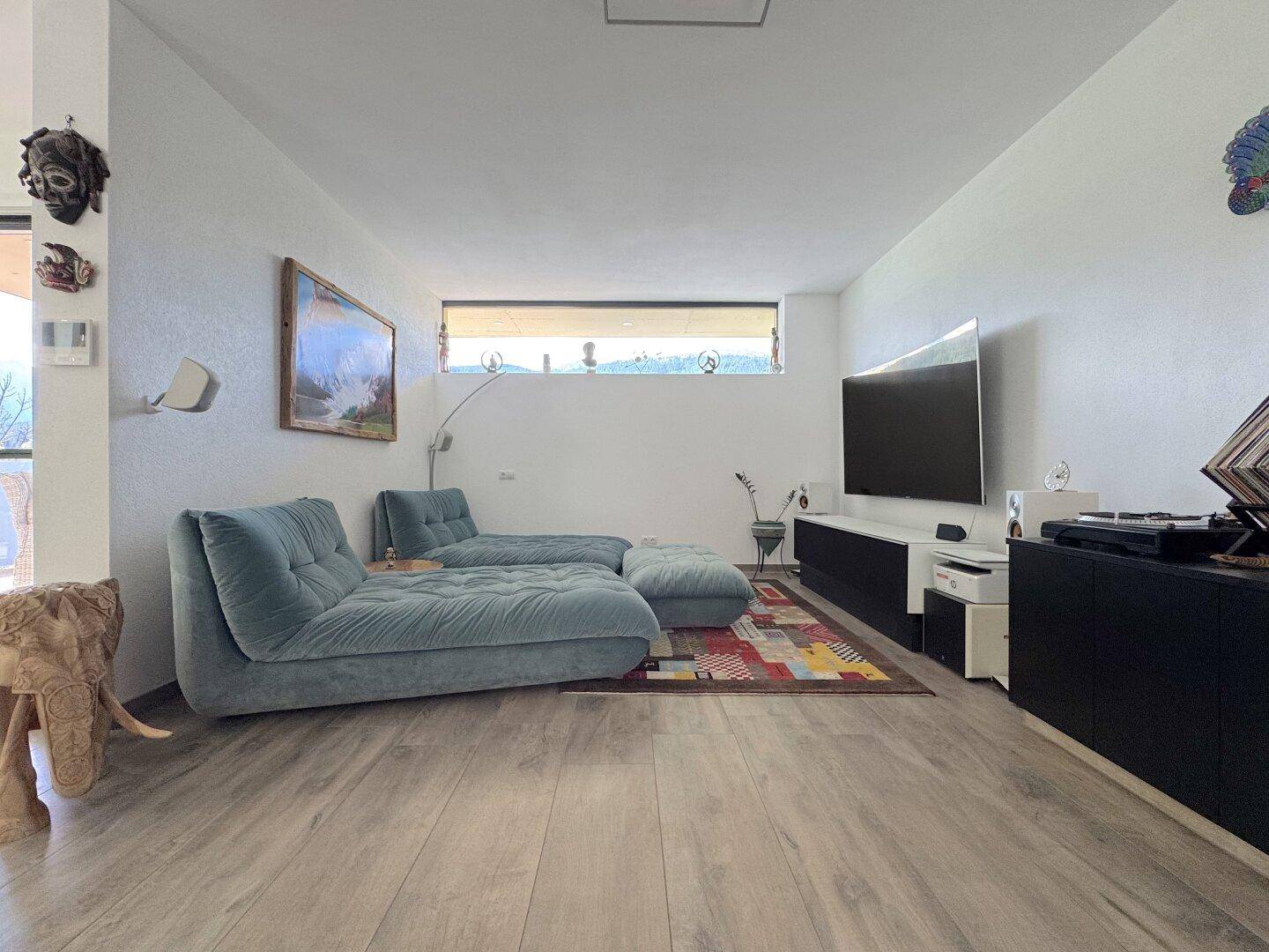 Gemütliches Wohnzimmer mit bequemen Sofas, Fernseher und einem farbenfrohen Teppich.