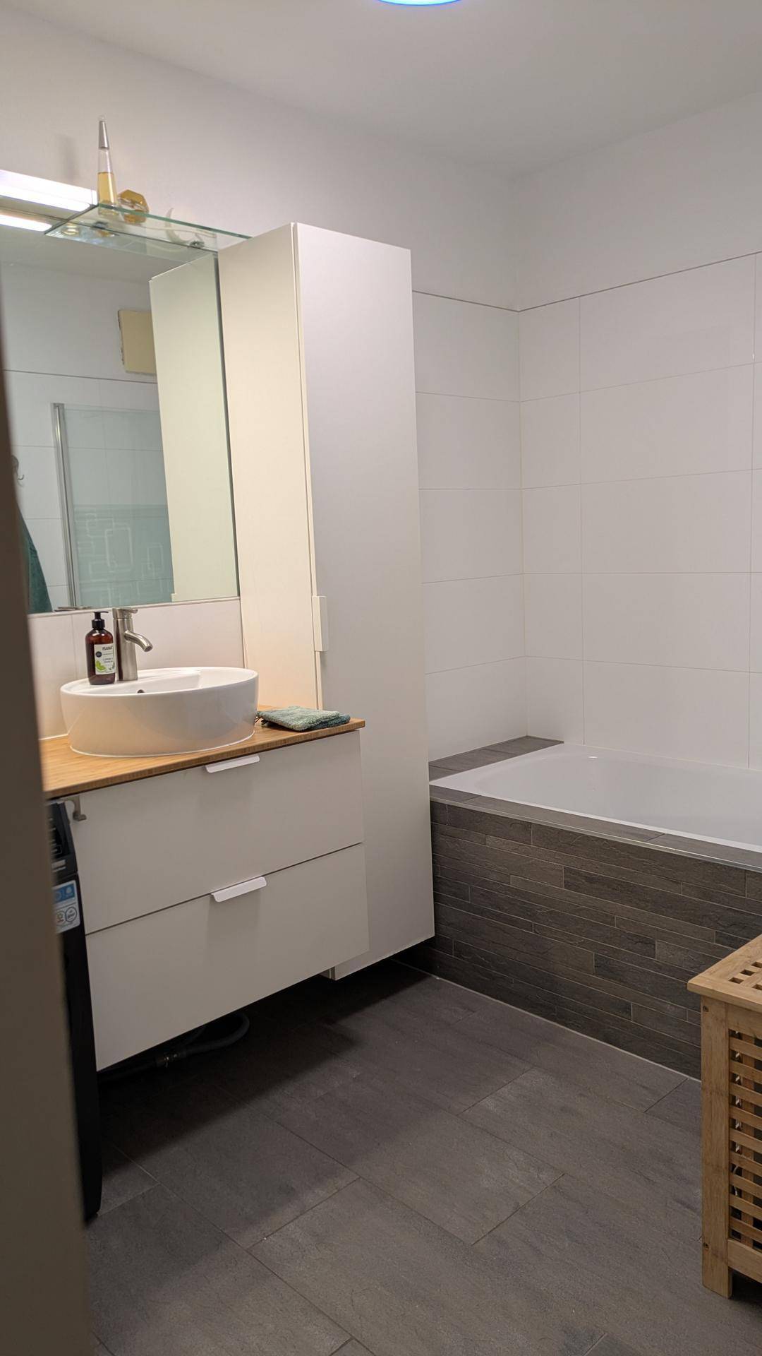 Modernes Badezimmer mit Badewanne, Einzelwaschbecken und hellen Fliesen.
