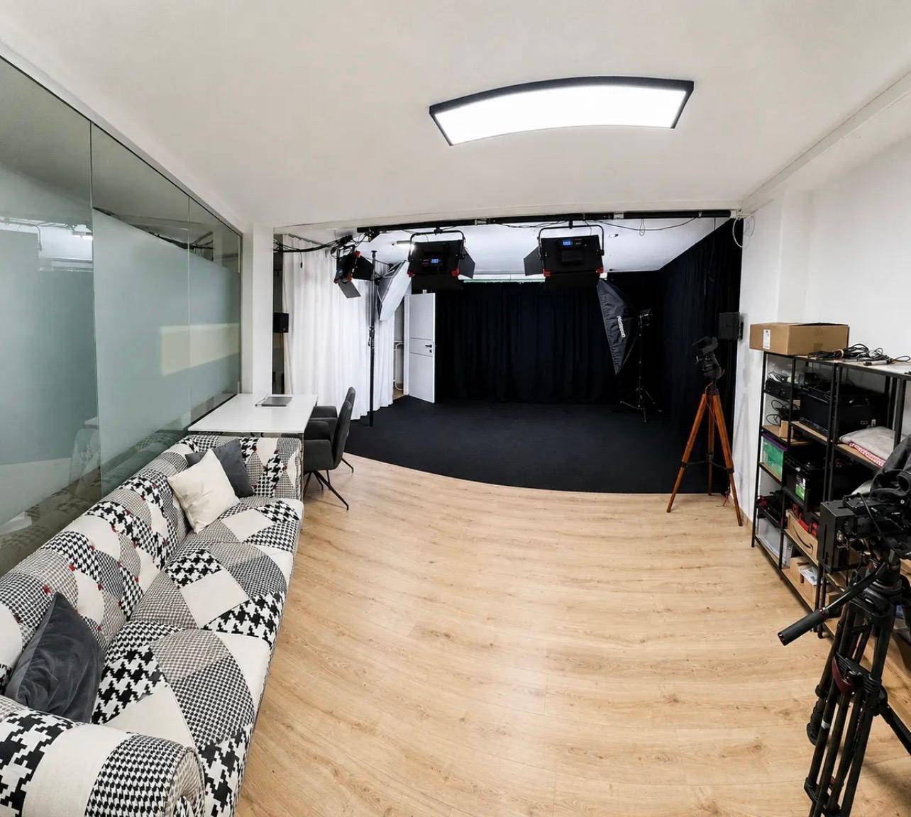 Vielseitiger Studiobereich mit professioneller Ausrüstung, einem Sofa und dunklem Hintergrund für Aufnahmen.