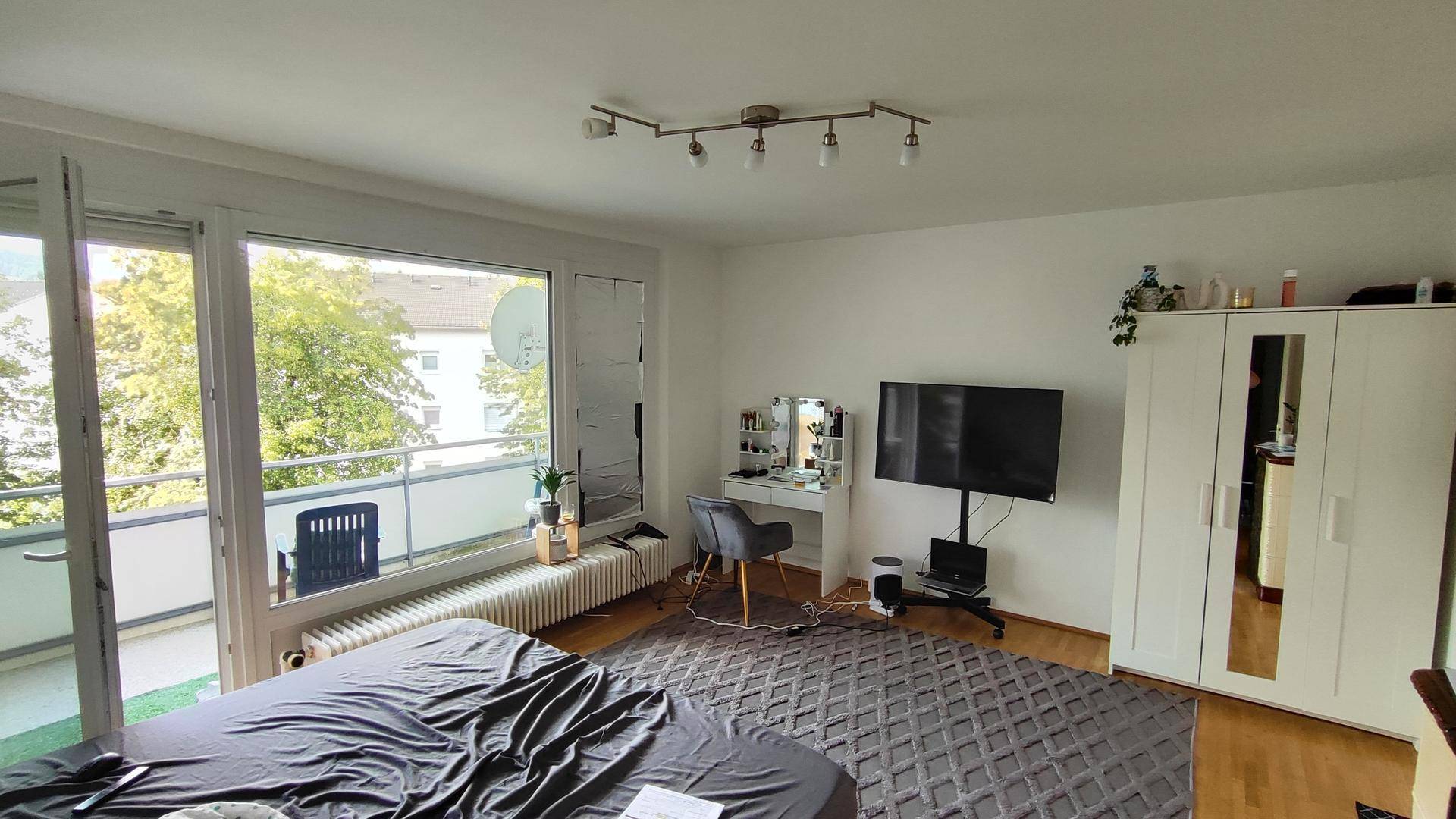 Helles Schlafzimmer mit großem Fenster, Balkonzugang und modernem Schminktisch.