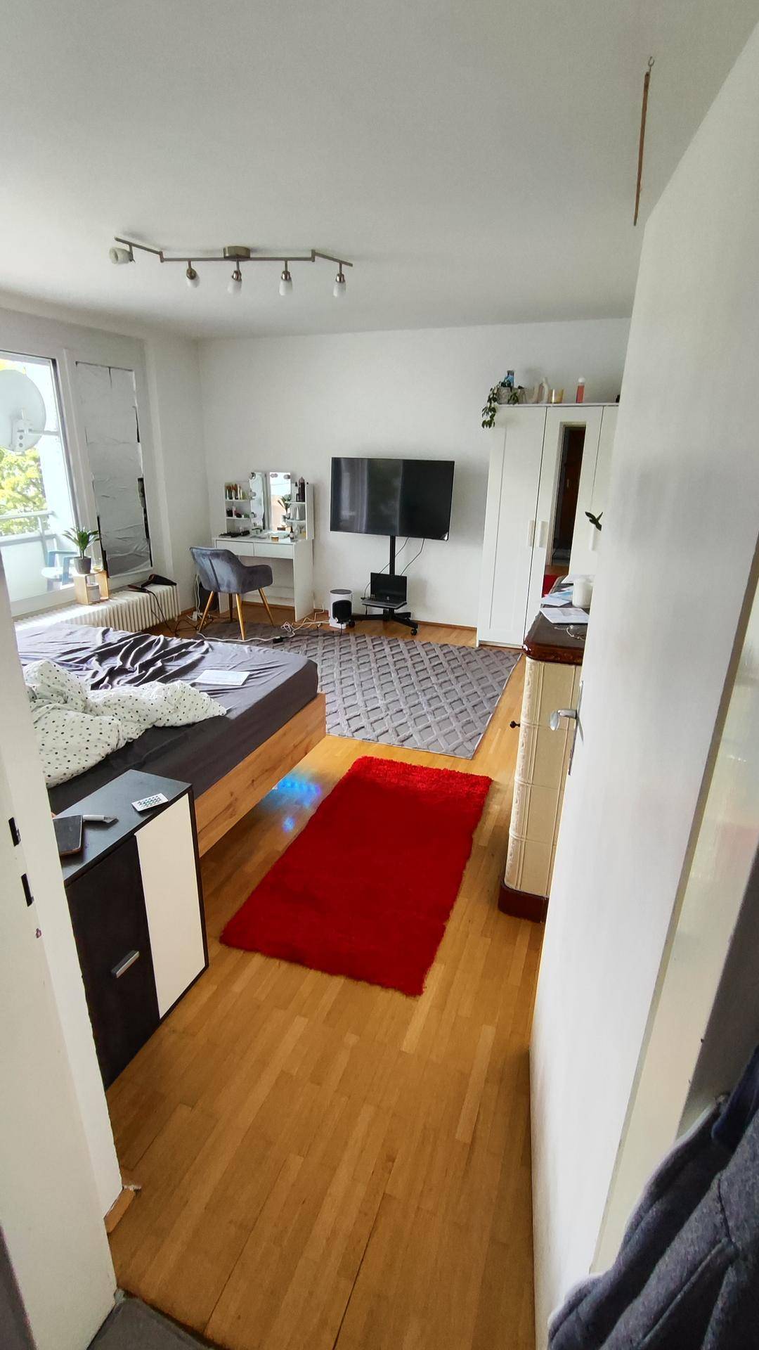 Schlafzimmer mit Holzbett, Teppich und Blick auf den Balkon.