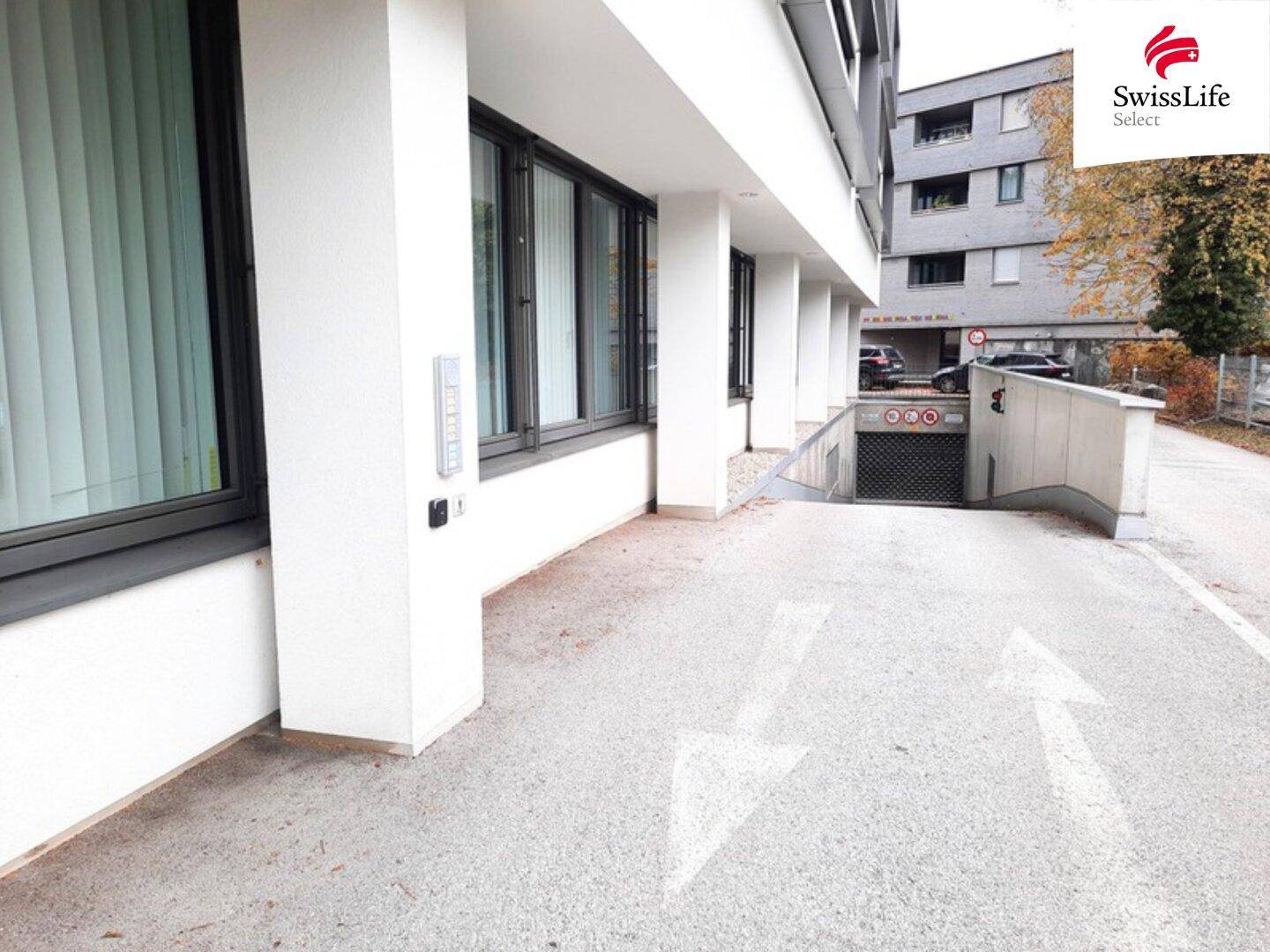 Außenbereich mit Zufahrt zu einer Tiefgarage und der modernen Fassade des Bürogebäudes.