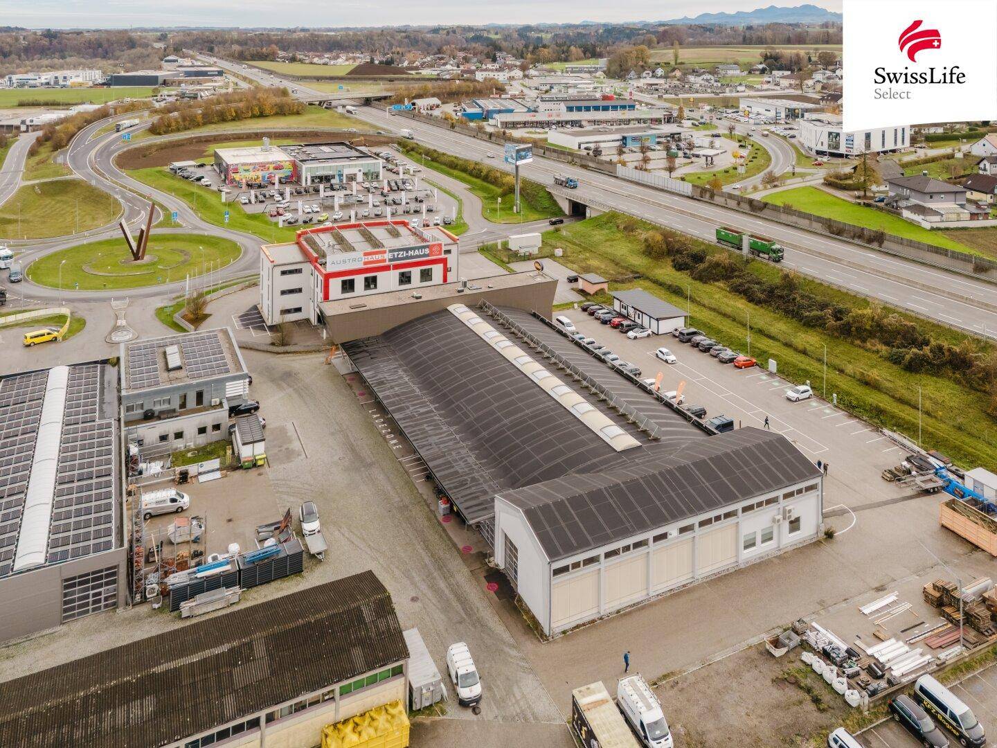 Luftaufnahme eines Industriegebiets mit mehreren Gebäuden, Parkplätzen und guter Verkehrsanbindung.
