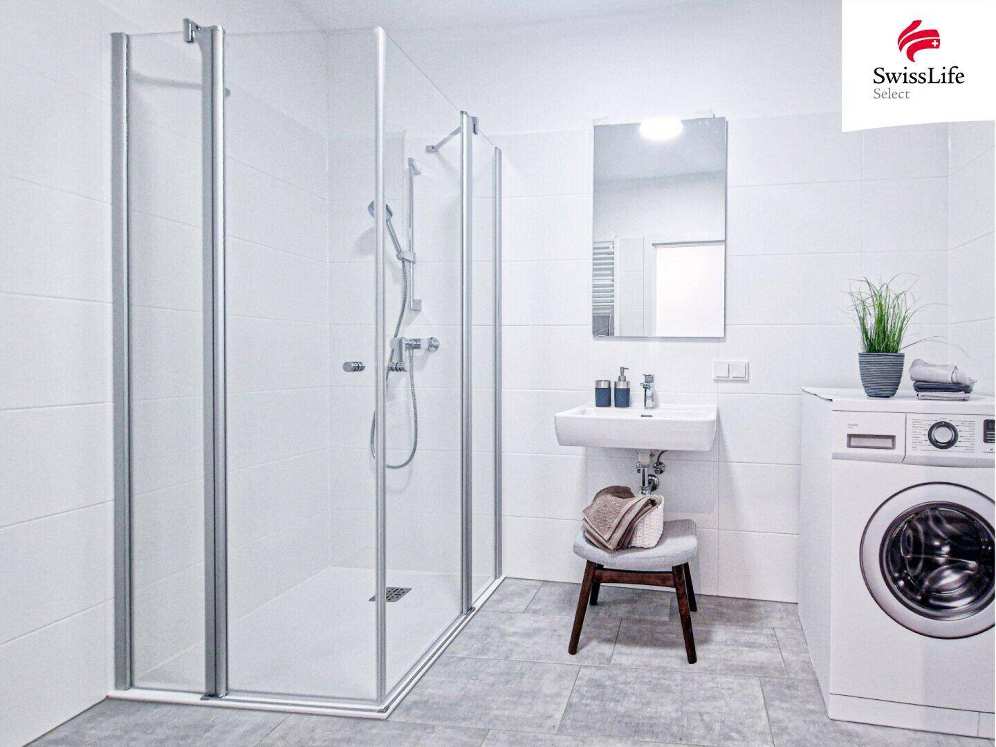 Modernes Badezimmer mit ebenerdiger Glasdusche, Waschbecken und Waschmaschine.