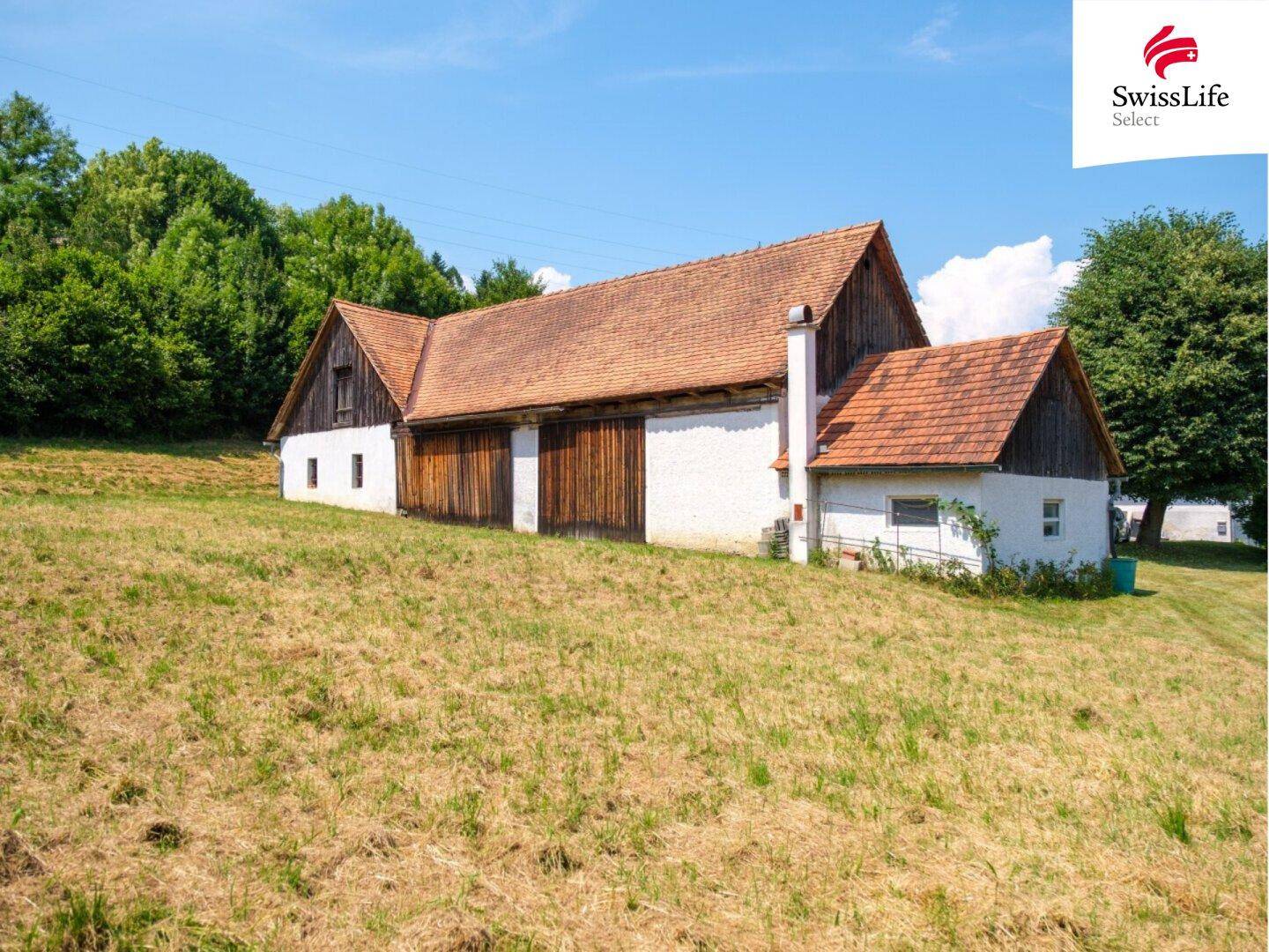 Bauernhaus mit Nebengebäuden auf einem weitläufigen, leicht abfallenden Grundstück.